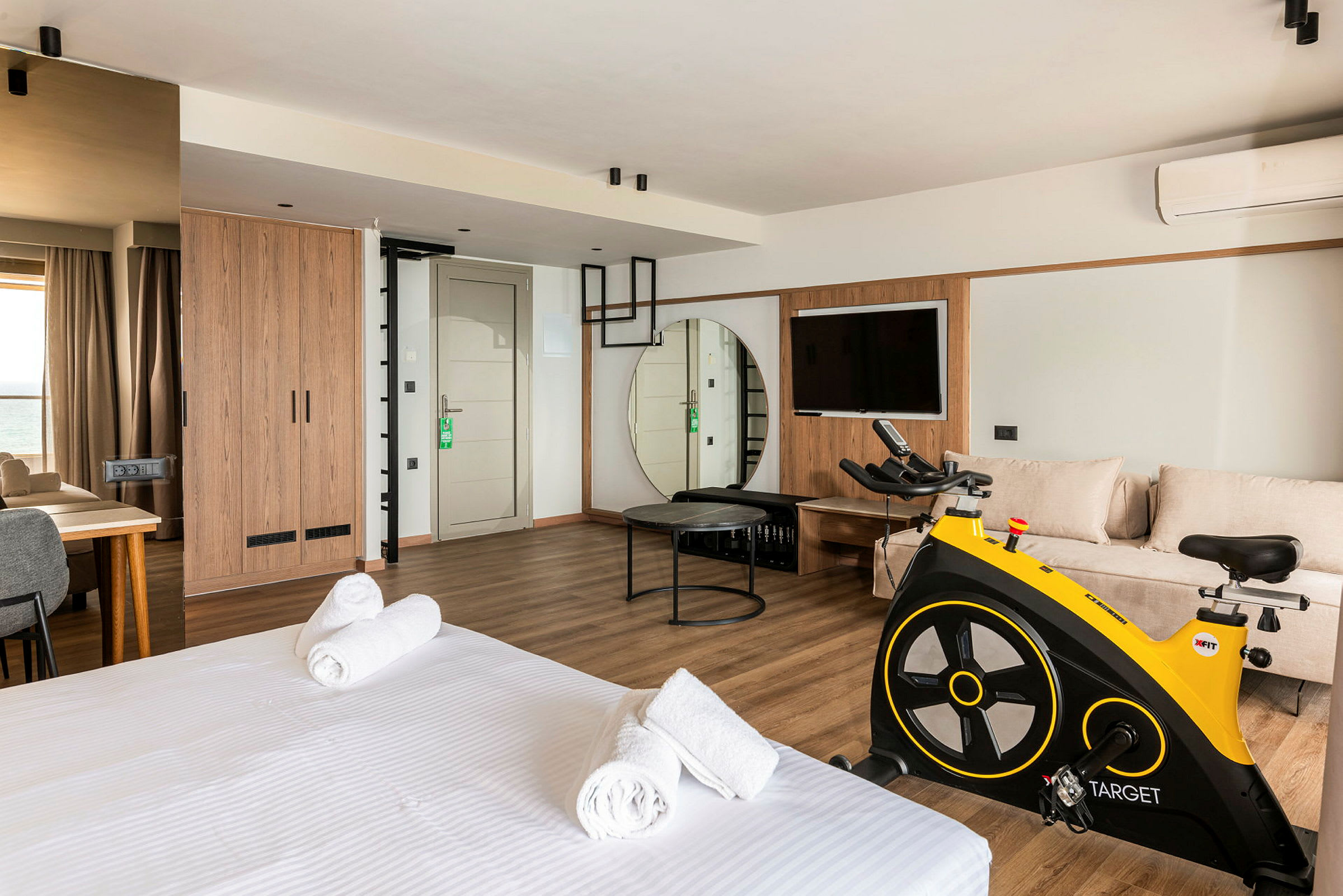 Et moderne hotelværelse med seng, siddeområde, motionscykel og TV. (AI-genereret tekst)