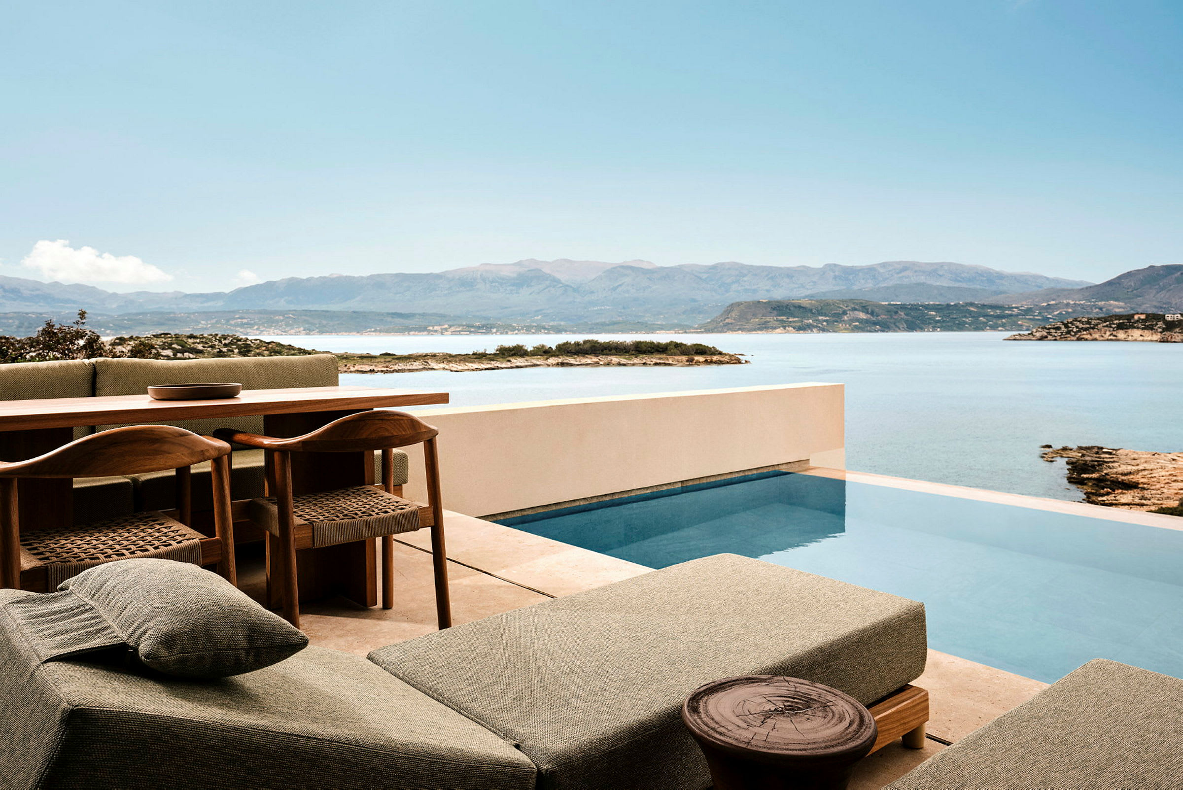 Terrasse med pool og udsigt over hav og bjerge. (AI-genereret tekst)