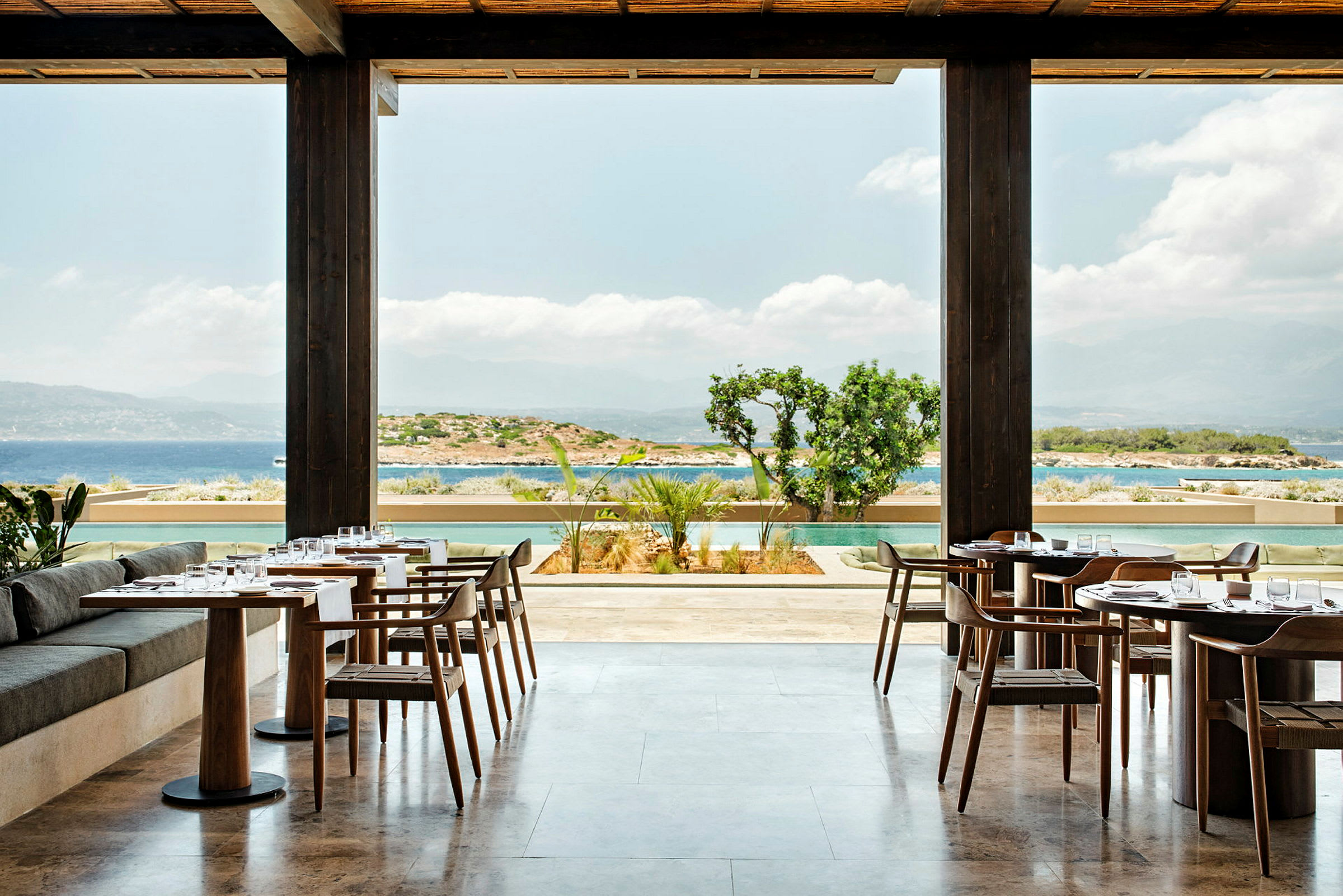 En restaurant med borde og stole med udsigt over havet og omgivelserne. (AI-genereret tekst)