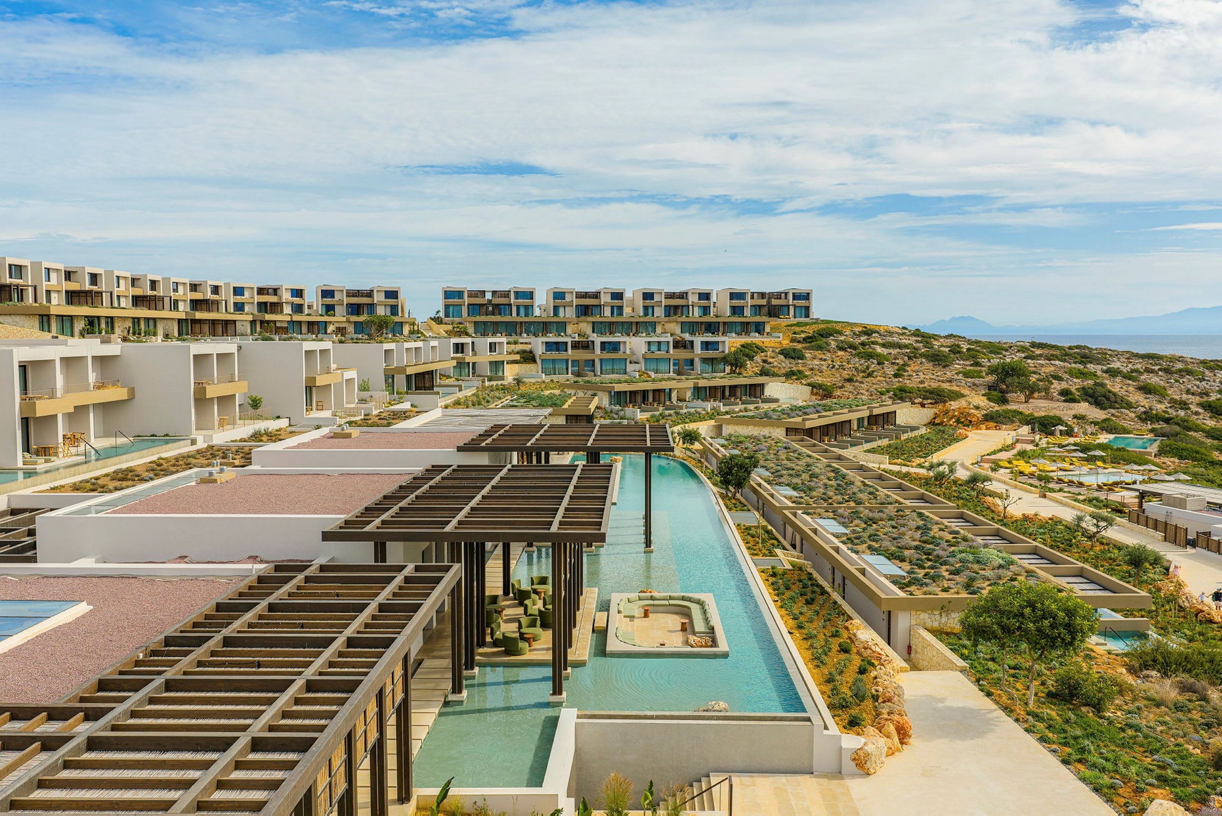 Billede af et moderne hotelkompleks med flere bygninger, poolområder og terrasserede haver. (AI-genereret tekst)