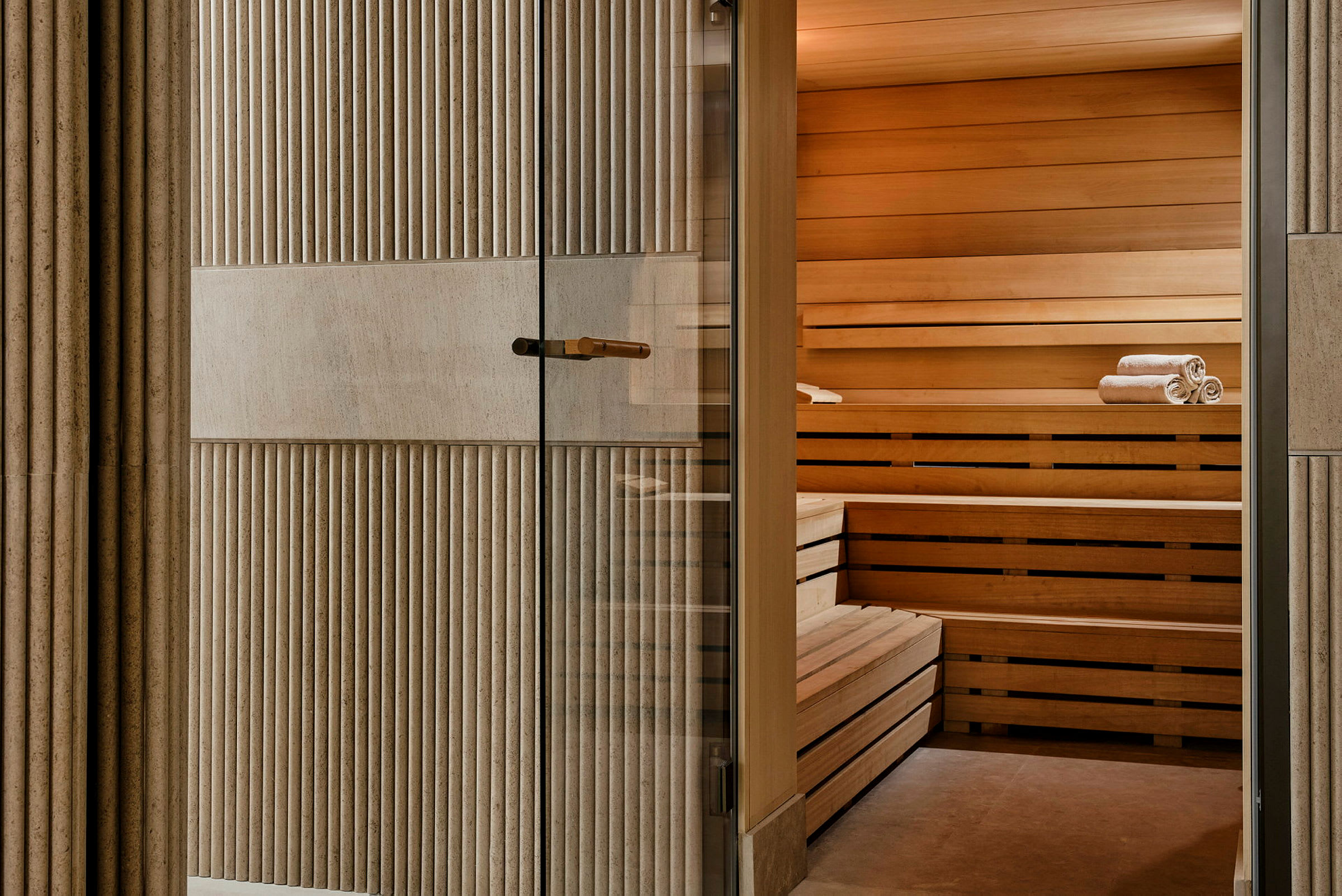 En sauna med træpaneler og sammenfoldede håndklæder på bænke. (AI-genereret tekst)
