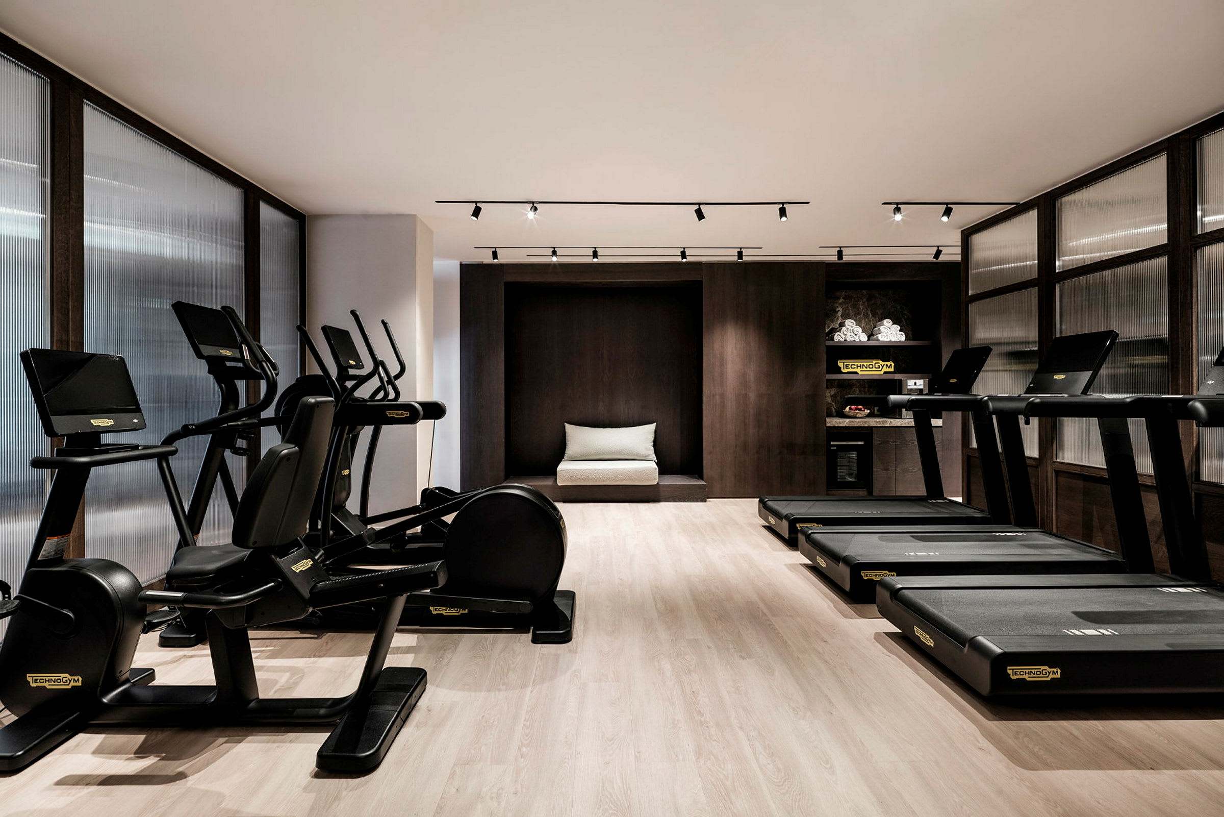 Et moderne fitnesscenter med træningsmaskiner og løbebånd placeret i et elegant indrettet rum. (AI-genereret tekst)
