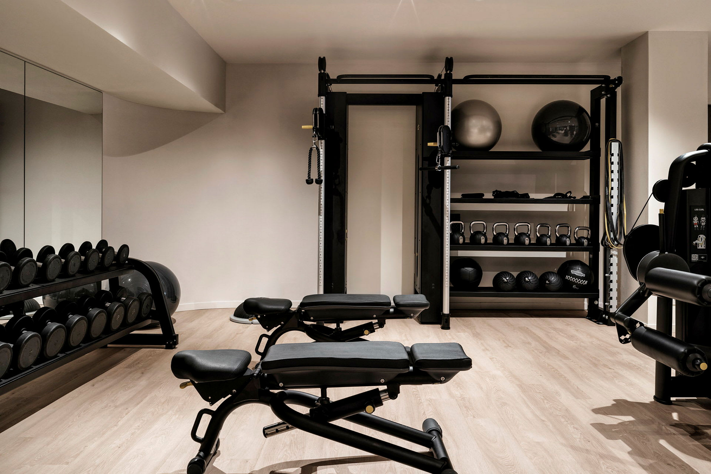 Et fitnessrum med udstyr såsom bænke, frie vægte og pilatesbolde. (AI-genereret tekst)