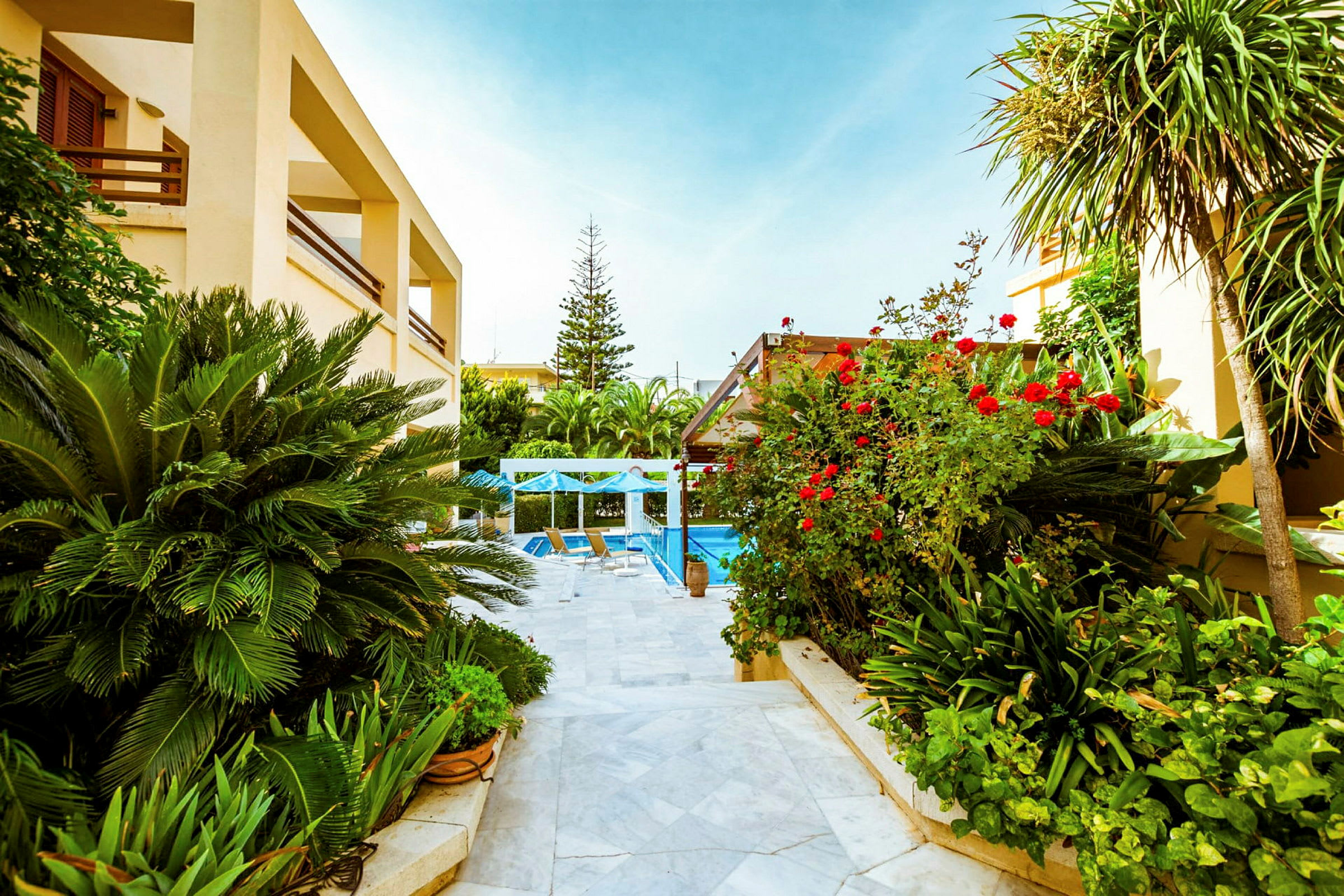 En have med frodig vegetation, blomster og en pool omgivet af terrasseområder. (AI-genereret tekst)