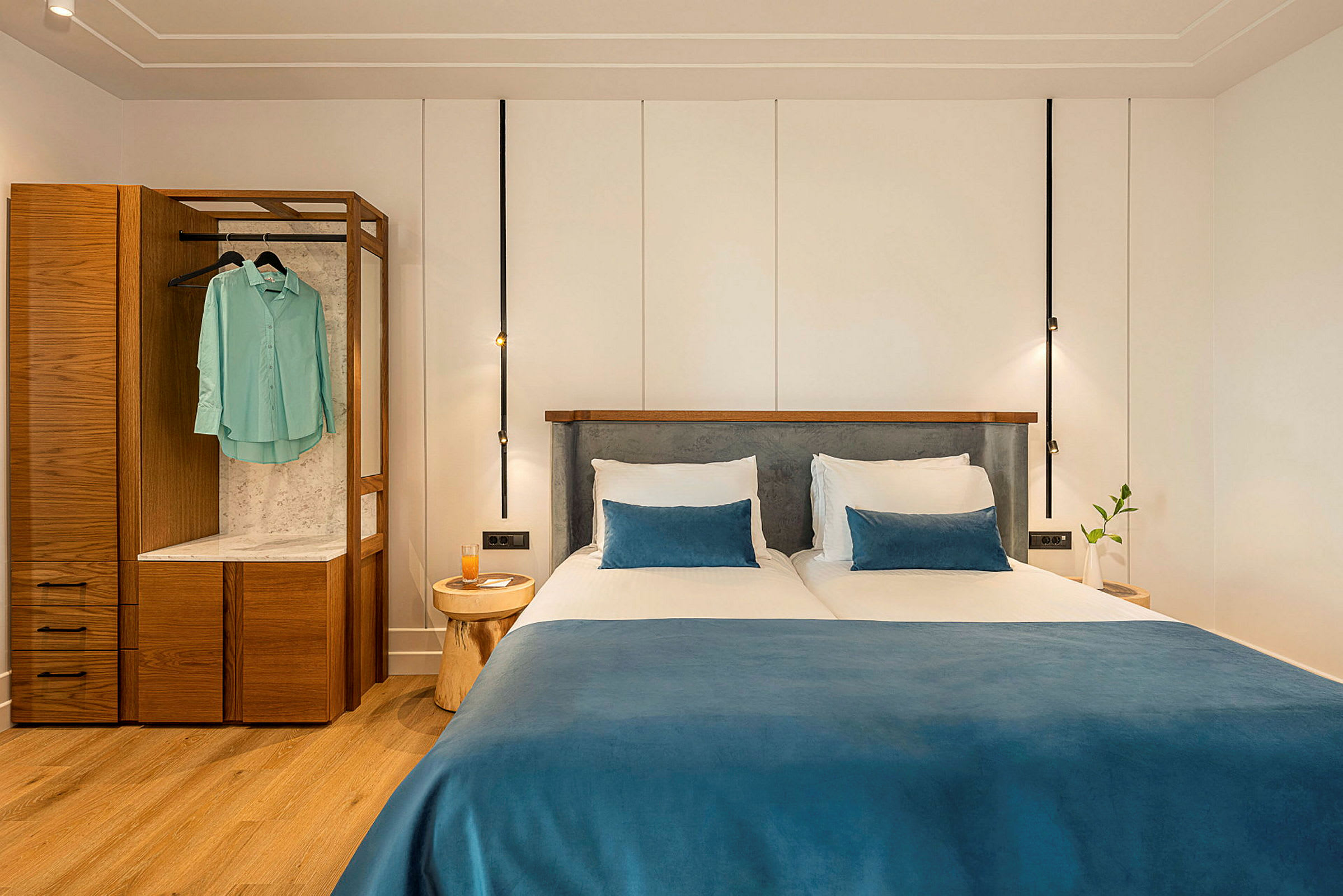 To enkeltsenge med blå sengetæpper og puder i et moderne hotelværelse. (AI-genereret tekst)