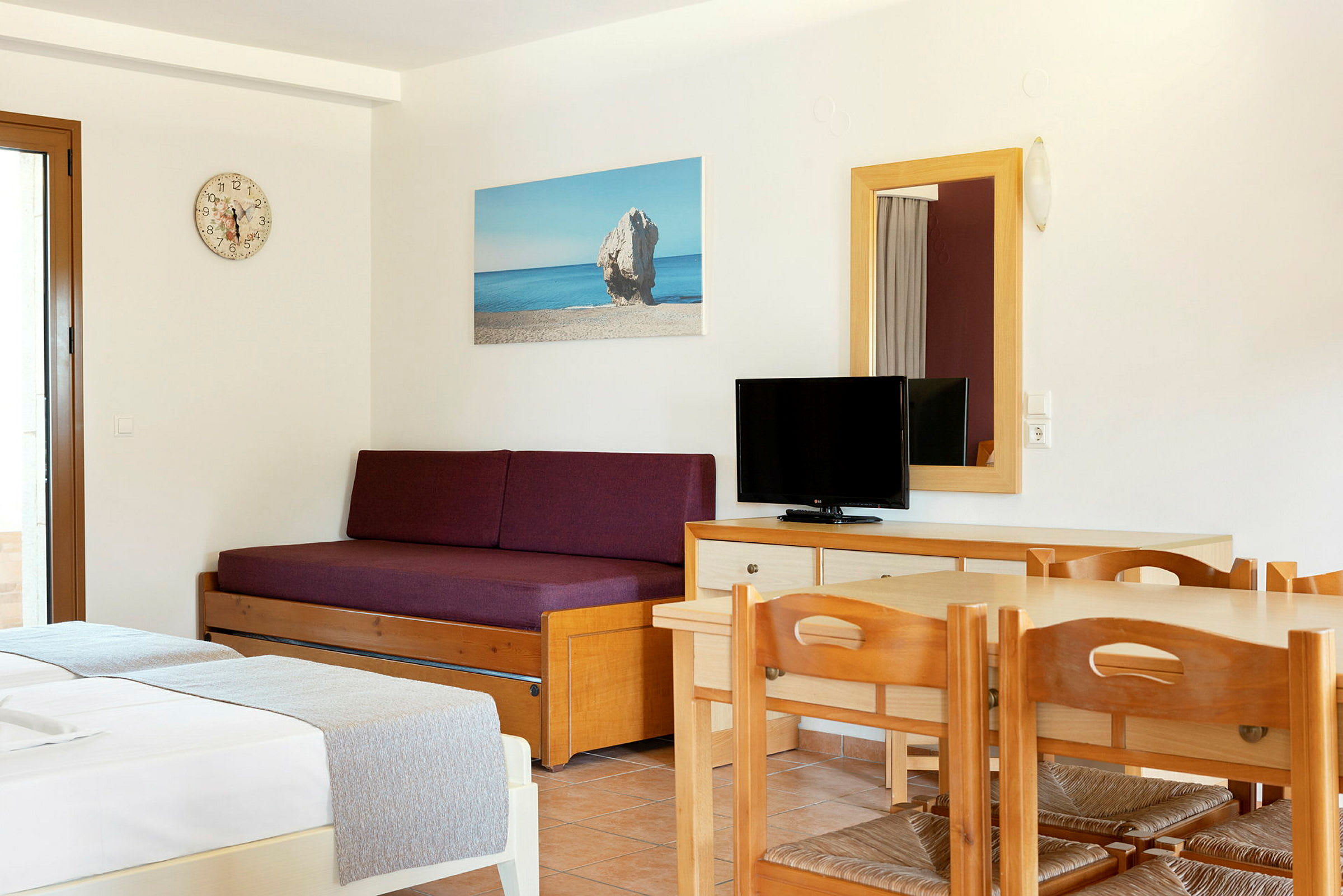 Indretning af et hotelværelse med en sovesofa, et bord med stole og et TV. (AI-genereret tekst)