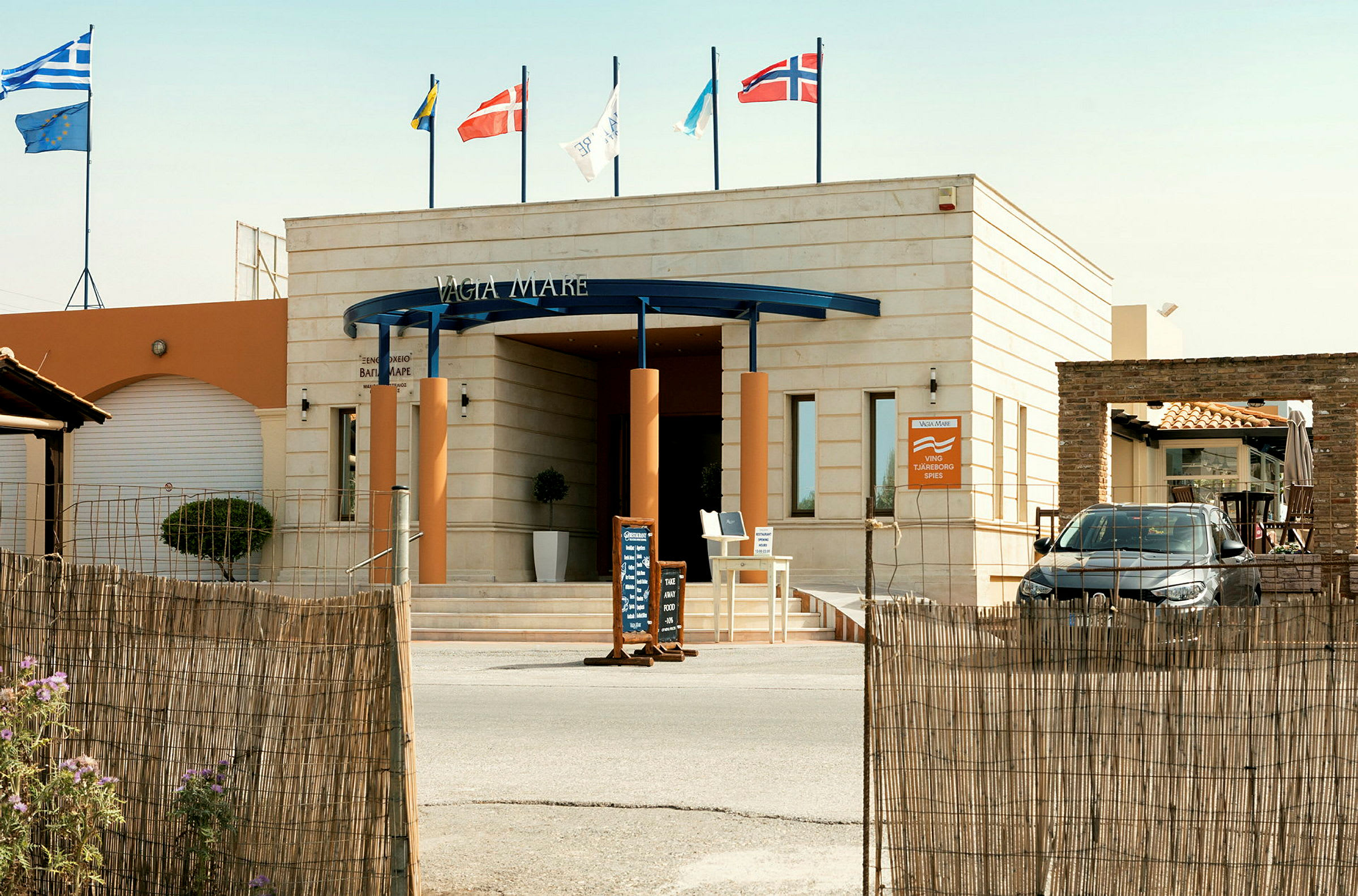 Indgang til et hotel med flag over. (AI-genereret tekst)
