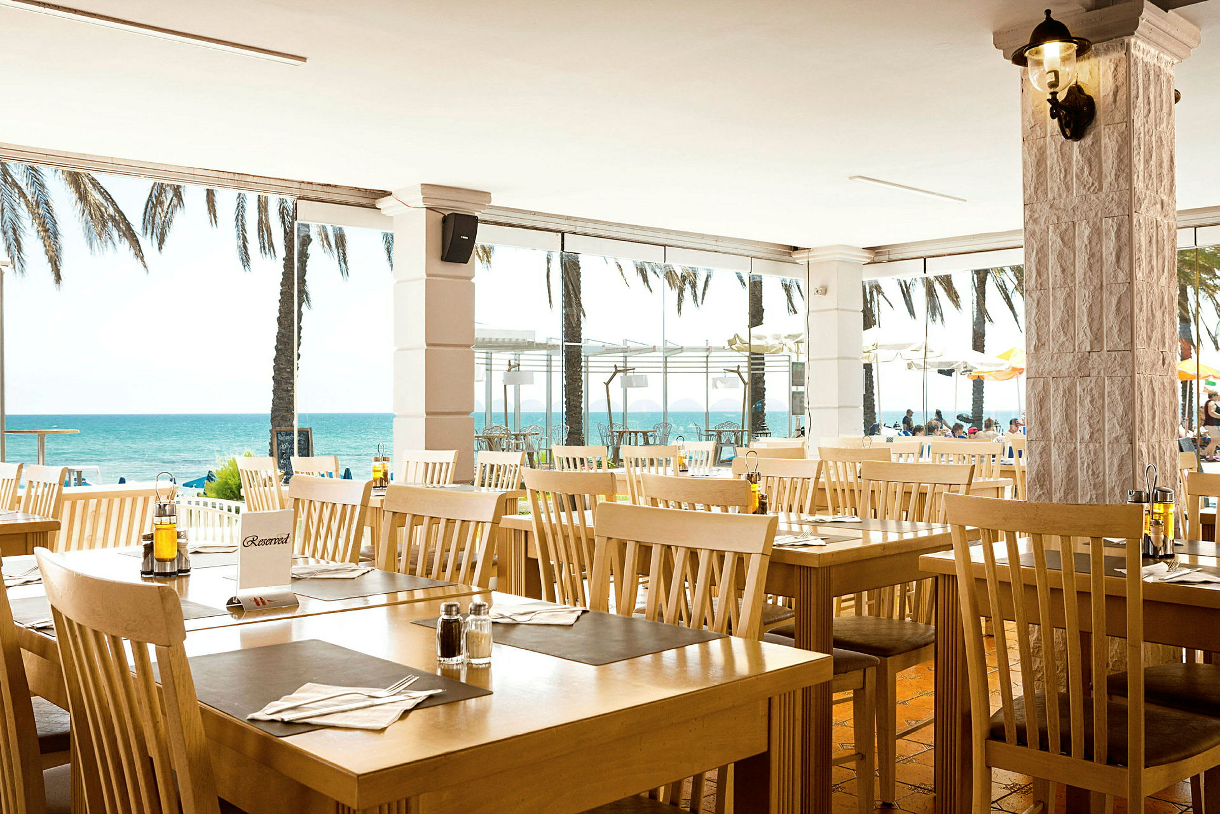Restaurant med træborde og stole ved stranden. (AI-genereret tekst)