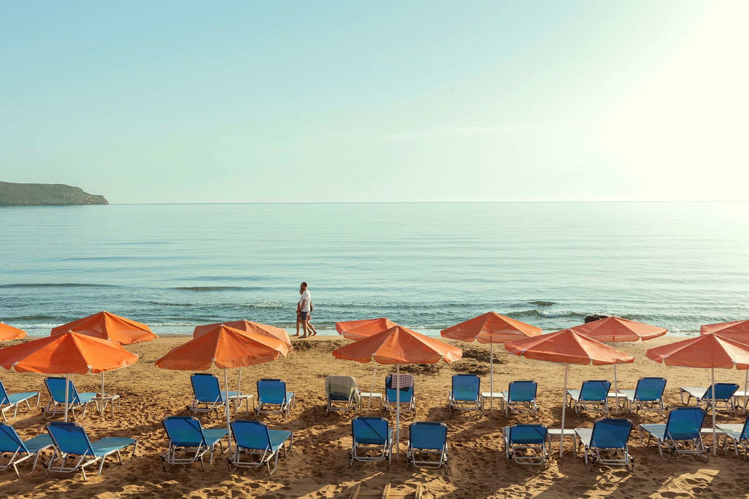 Liggestole og parasoller på en strand ved havet. (AI-genereret tekst)