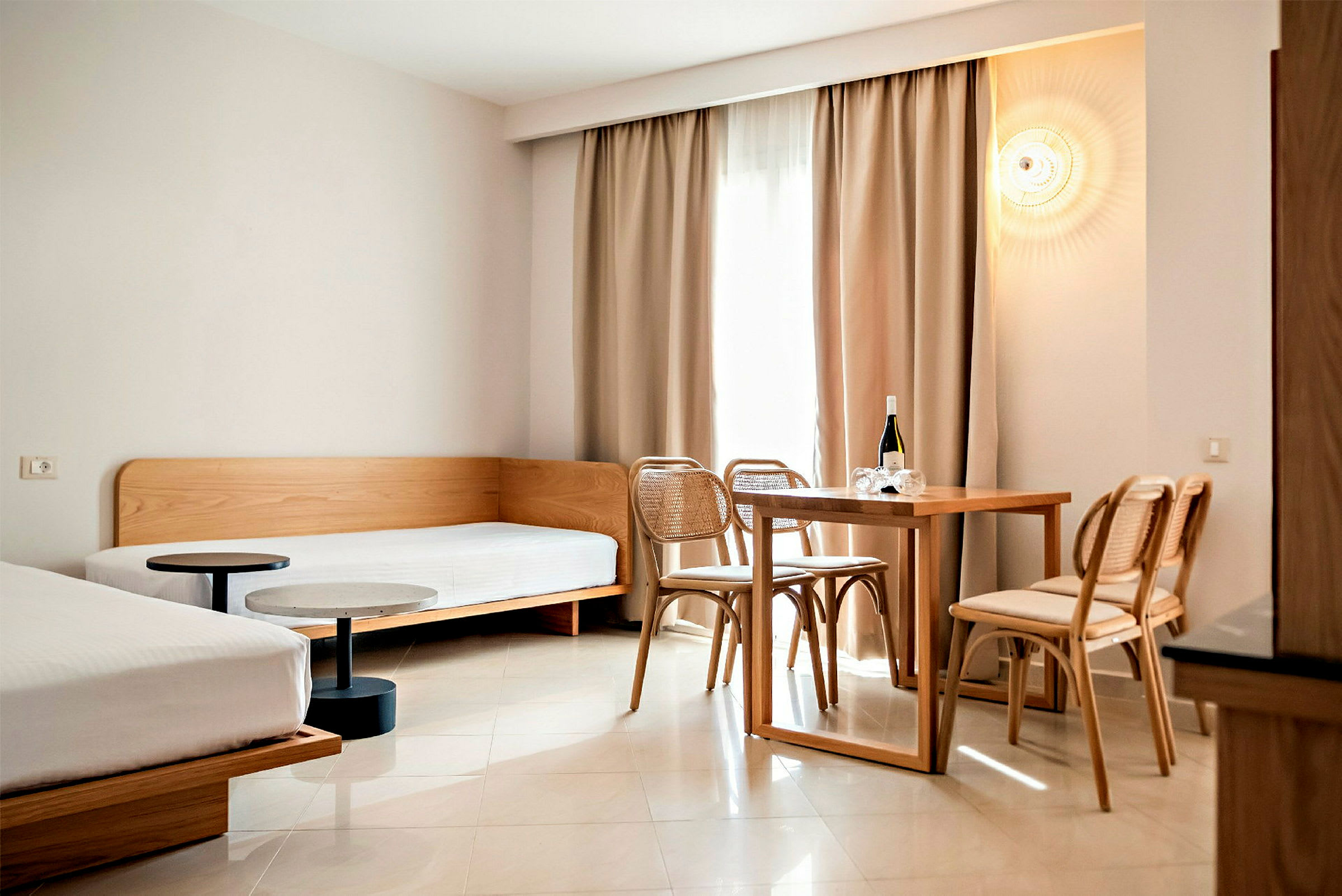 Et moderne indrettet hotelværelse med to senge og et spisebord med stole. (AI-genereret tekst)