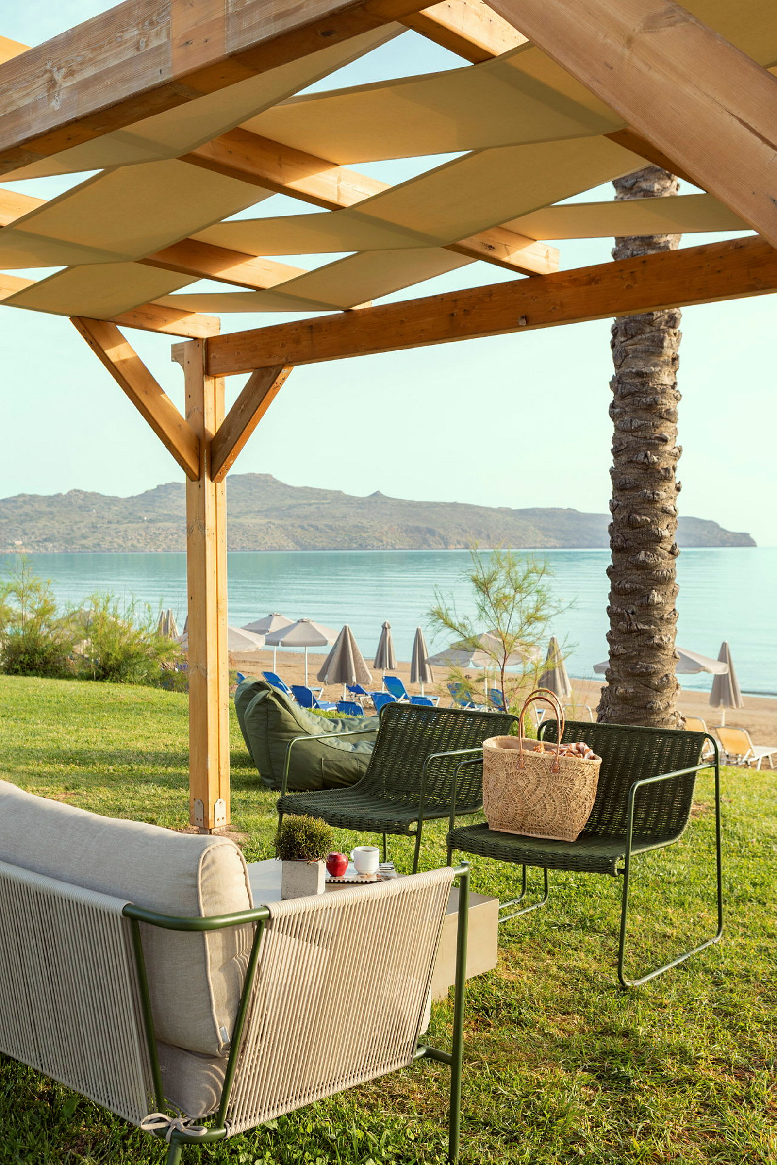 Havemøbler under en træpergola med udsigt til stranden og havet. (AI-genereret tekst)