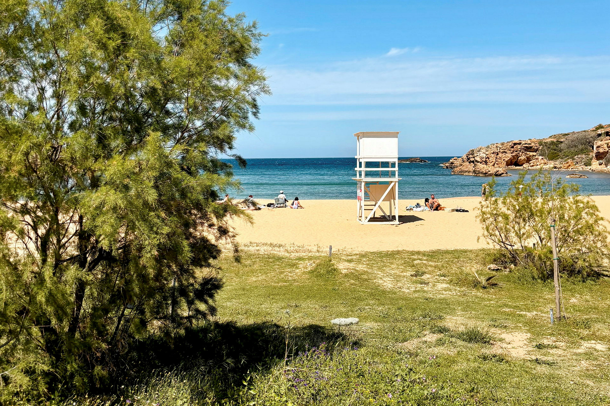 En sandstrand med badegæster, et livreddertårn og udsigt over havet. (AI-genereret tekst)