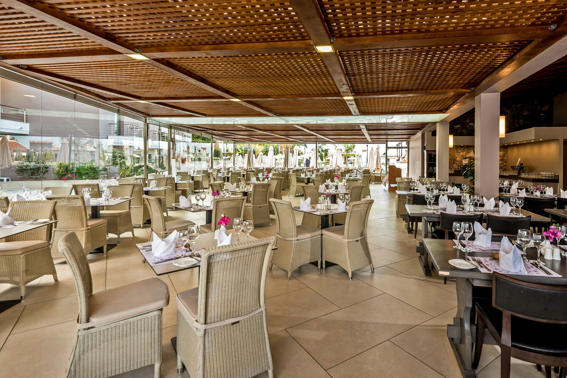 Restaurant med dækkede borde og stole under en træpergola. (AI-genereret tekst)