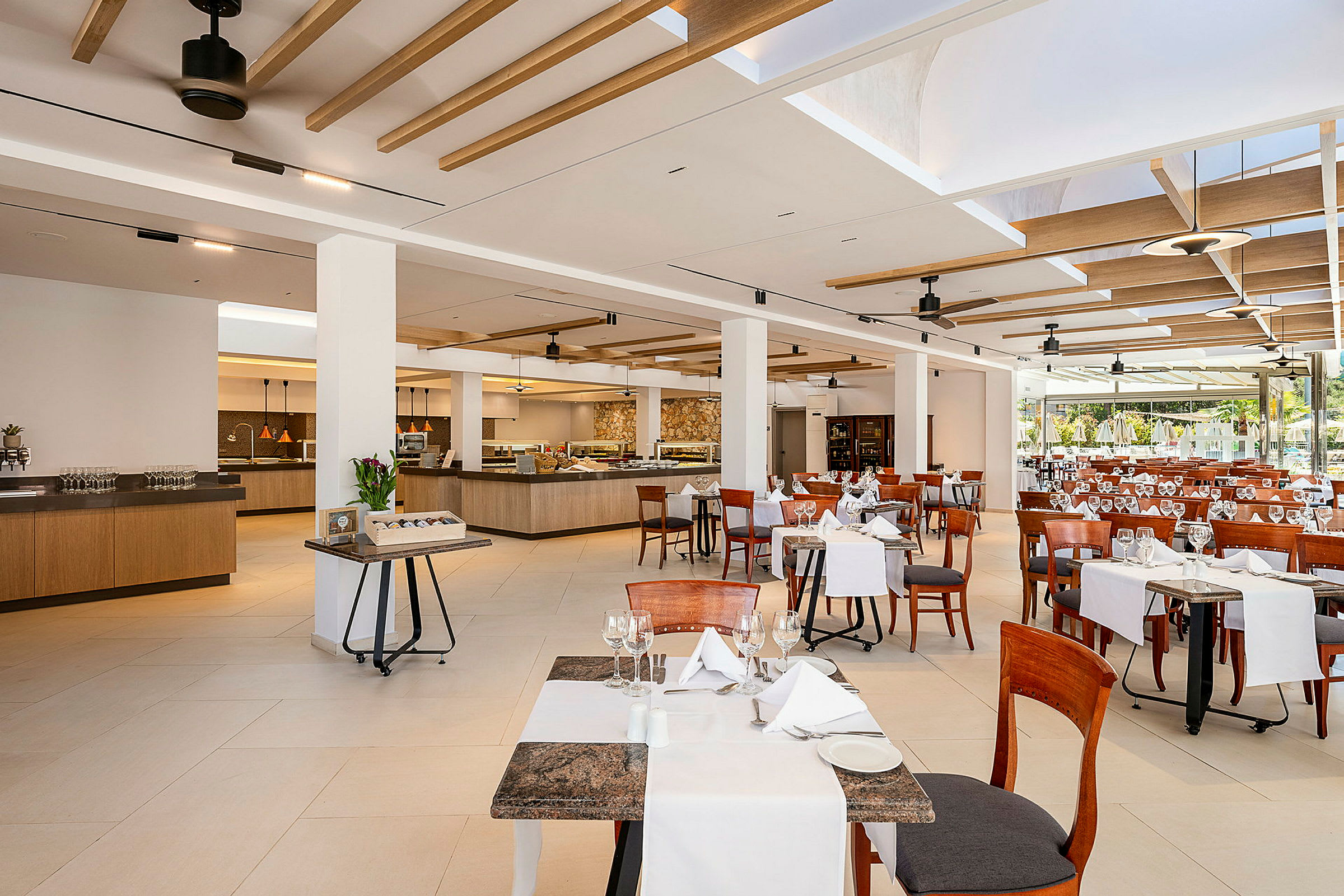 Billede af en rummelig restaurant med dækkede borde og stole samt serveringsområder i baggrunden. (AI-genereret tekst)