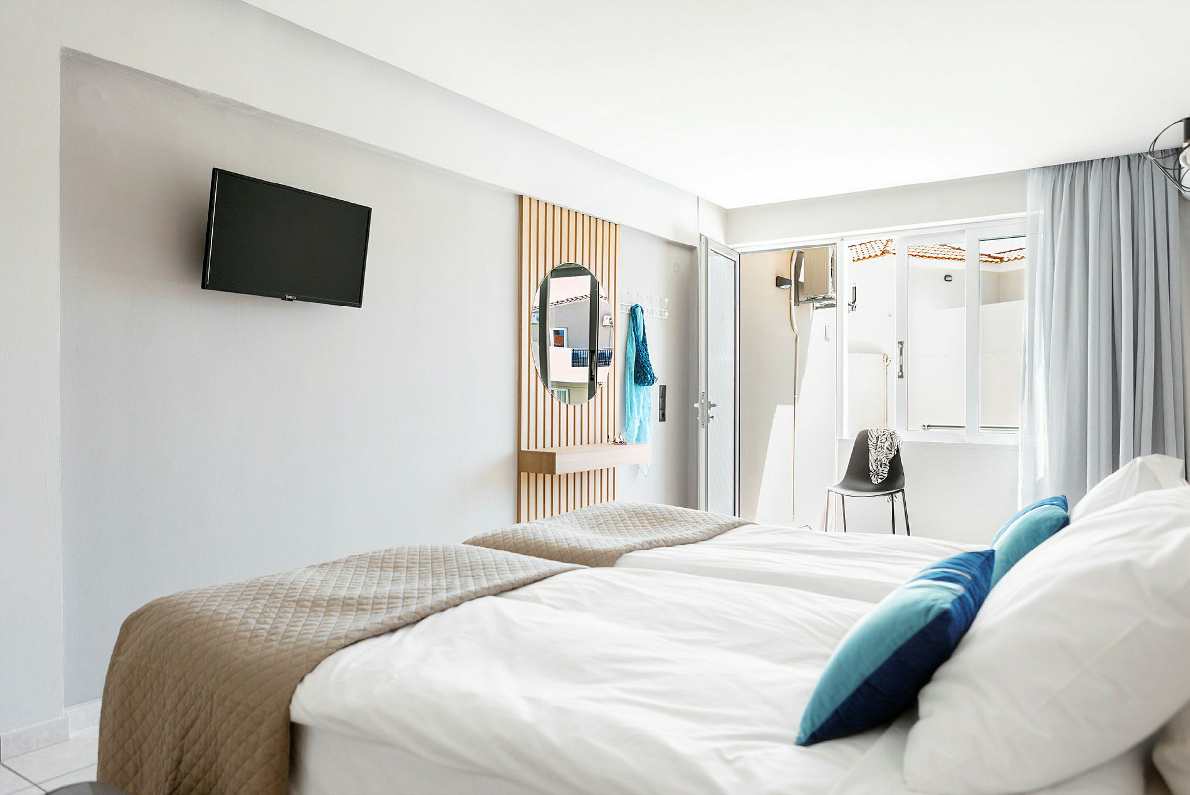 Hotelværelse med senge, tv på væggen og et spejl. (AI-genereret tekst)