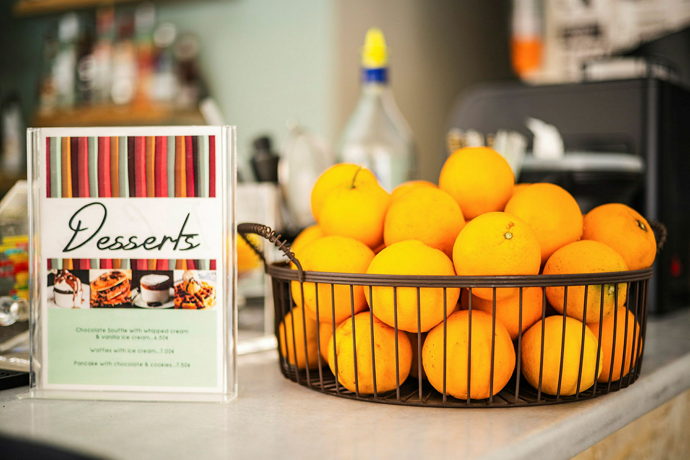 En kurv med appelsiner står ved siden af en dessertmenu. (AI-genereret tekst)