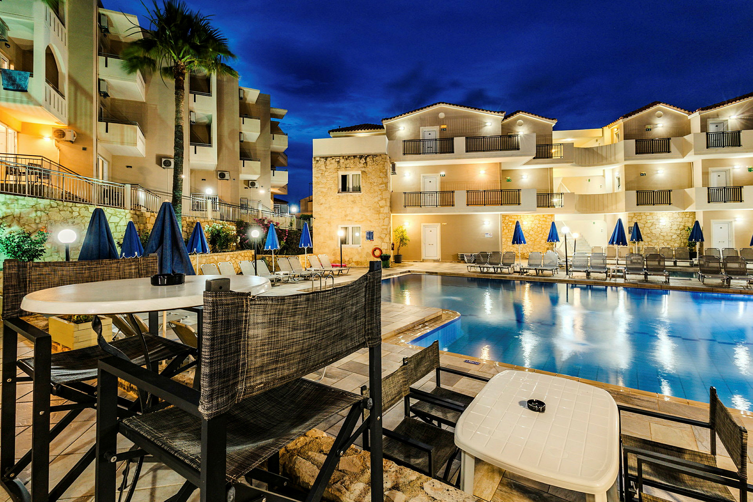 Et hotel med en udendørs pool og liggestole ved natbelysning. (AI-genereret tekst)
