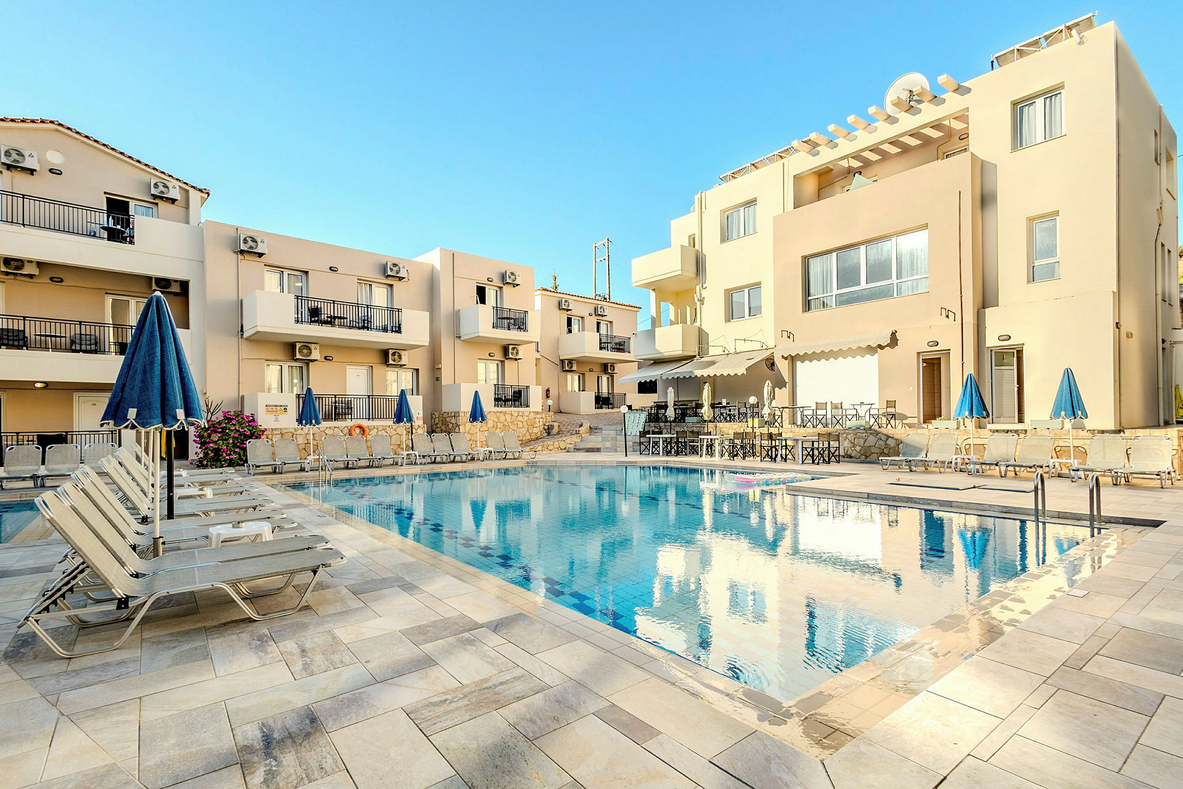 En udendørs pool ved et hotel med solsenge og parasoller. (AI-genereret tekst)