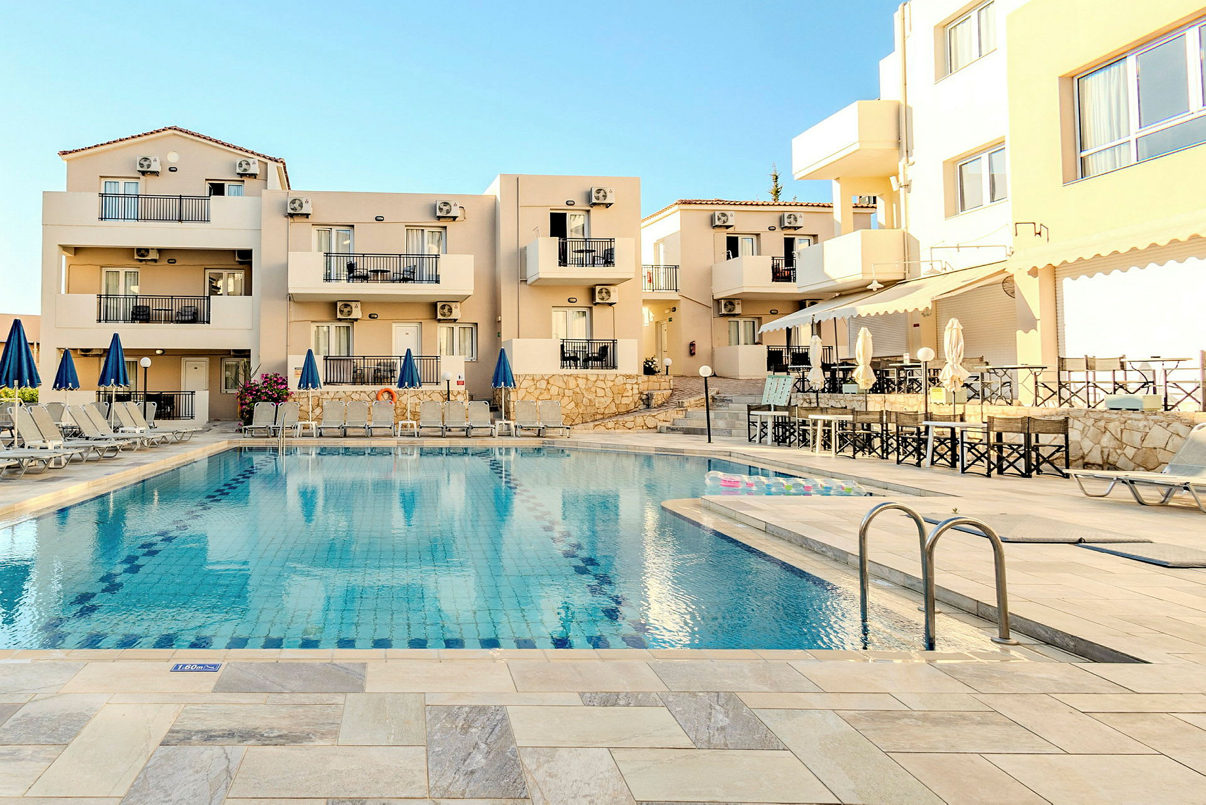 Hotelområde ved en pool med stole og parasoller. (AI-genereret tekst)