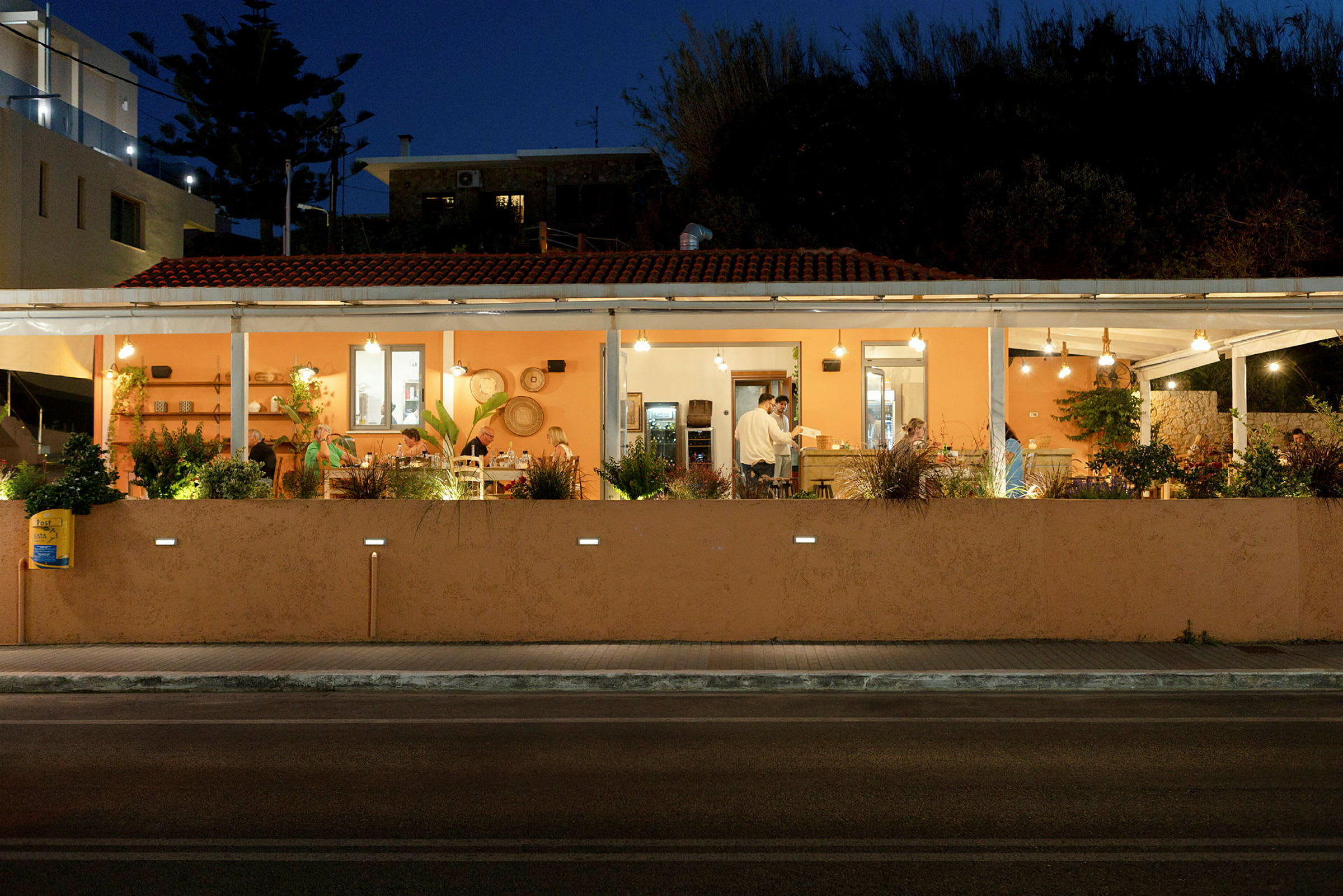 Udendørs restaurant med orange facade og udendørsservering i nattelys. (AI-genereret tekst)