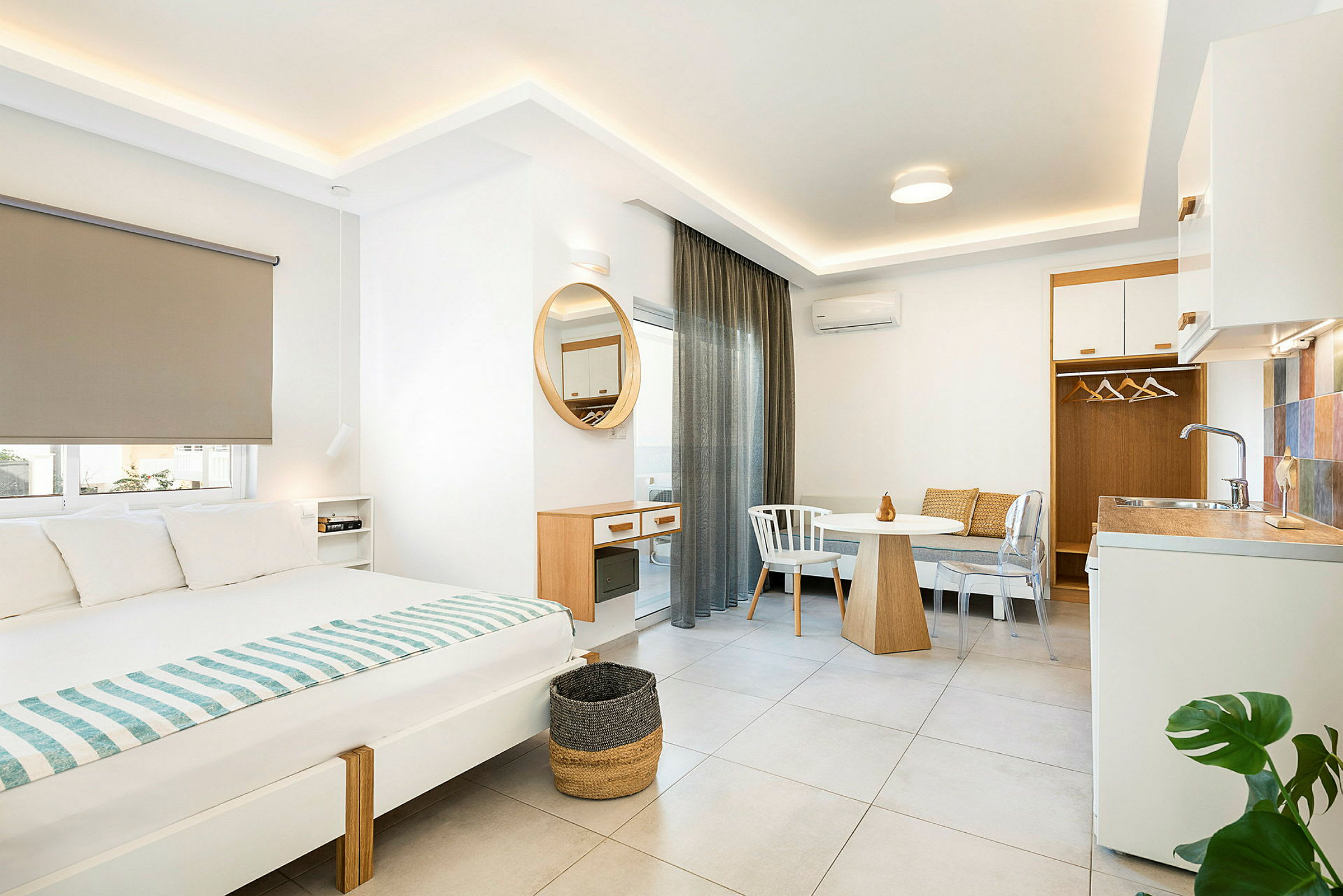 Interiør af et moderne hotelværelse med seng, spisebord og lille køkkenområde. (AI-genereret tekst)