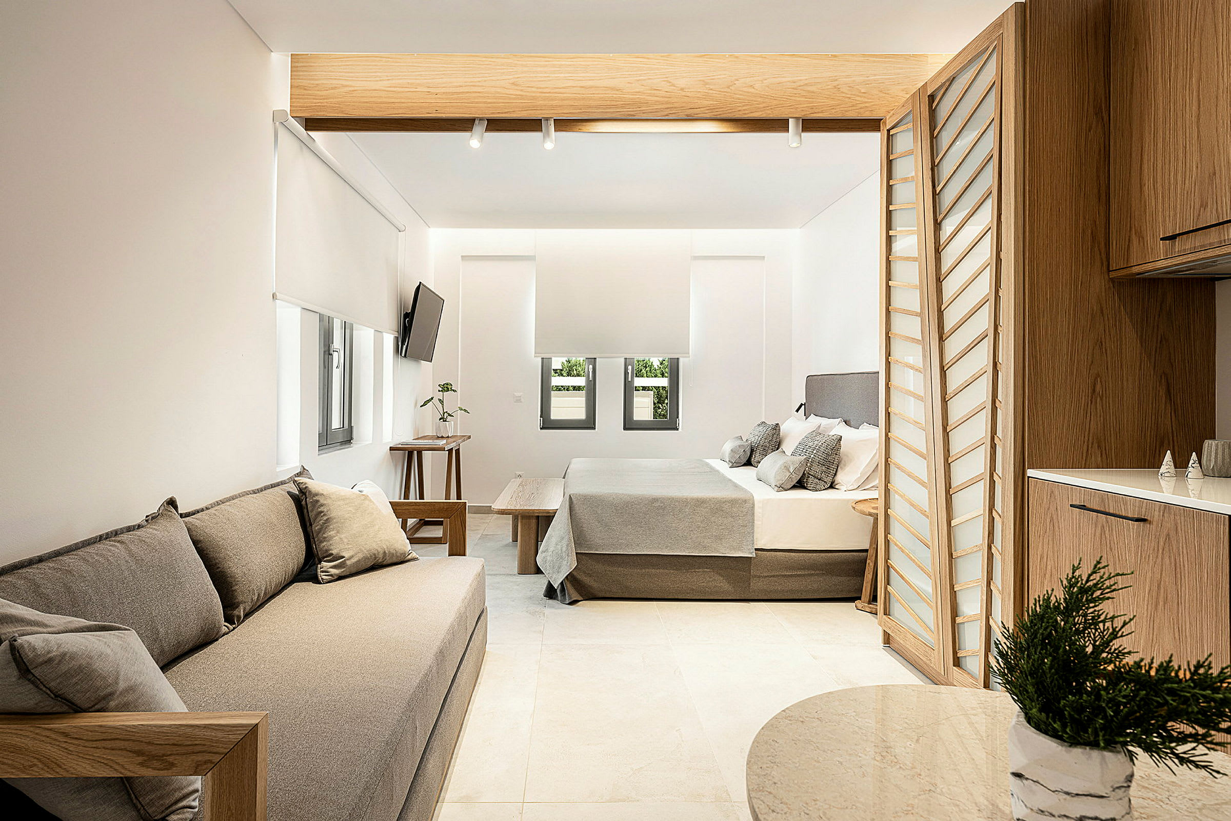Moderne indrettet hotelsuite med siddeplads, seng og køkkenområde. (AI-genereret tekst)