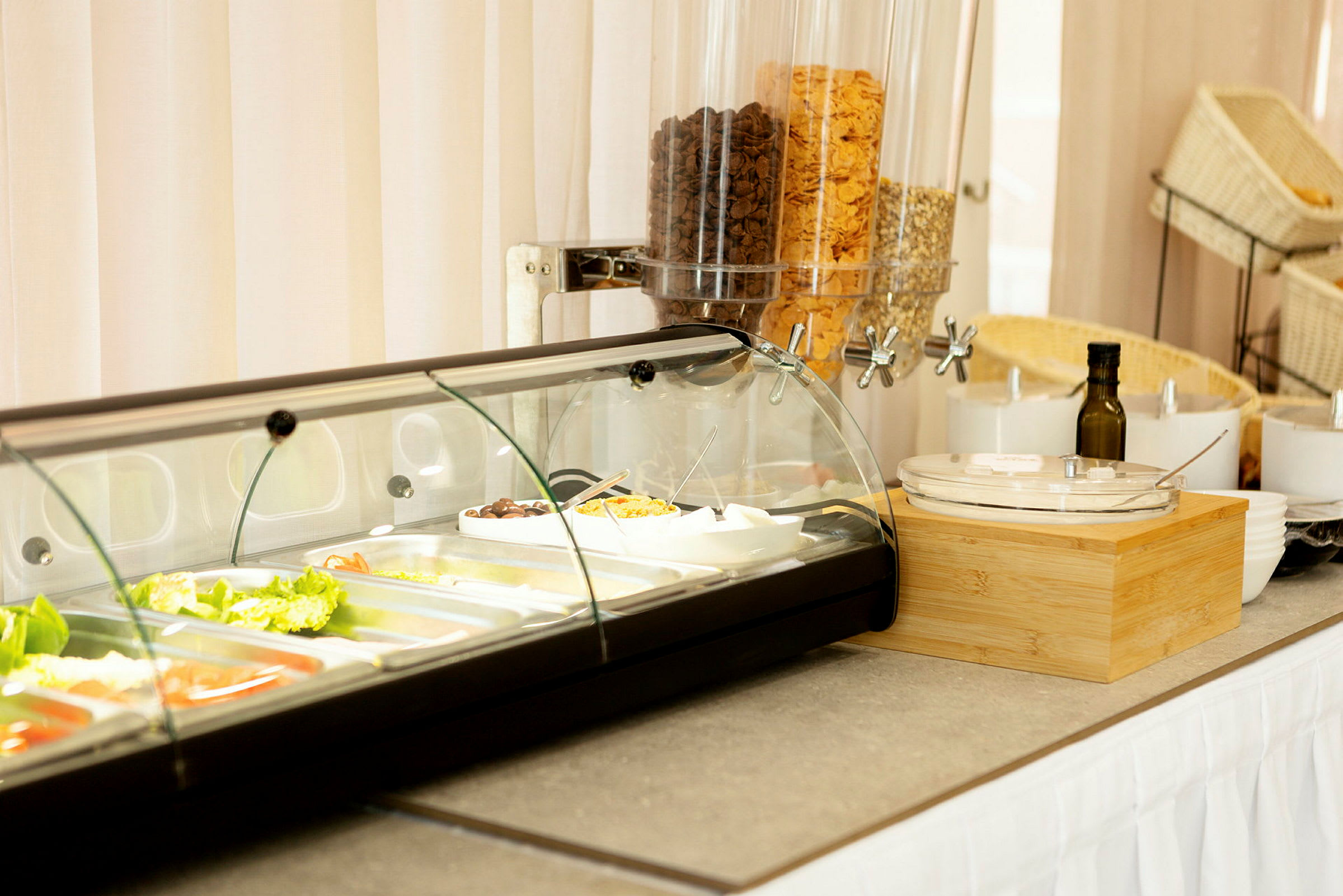 En buffet med salatingredienser i glasbeholdere og korn i dispensere. (AI-genereret tekst)