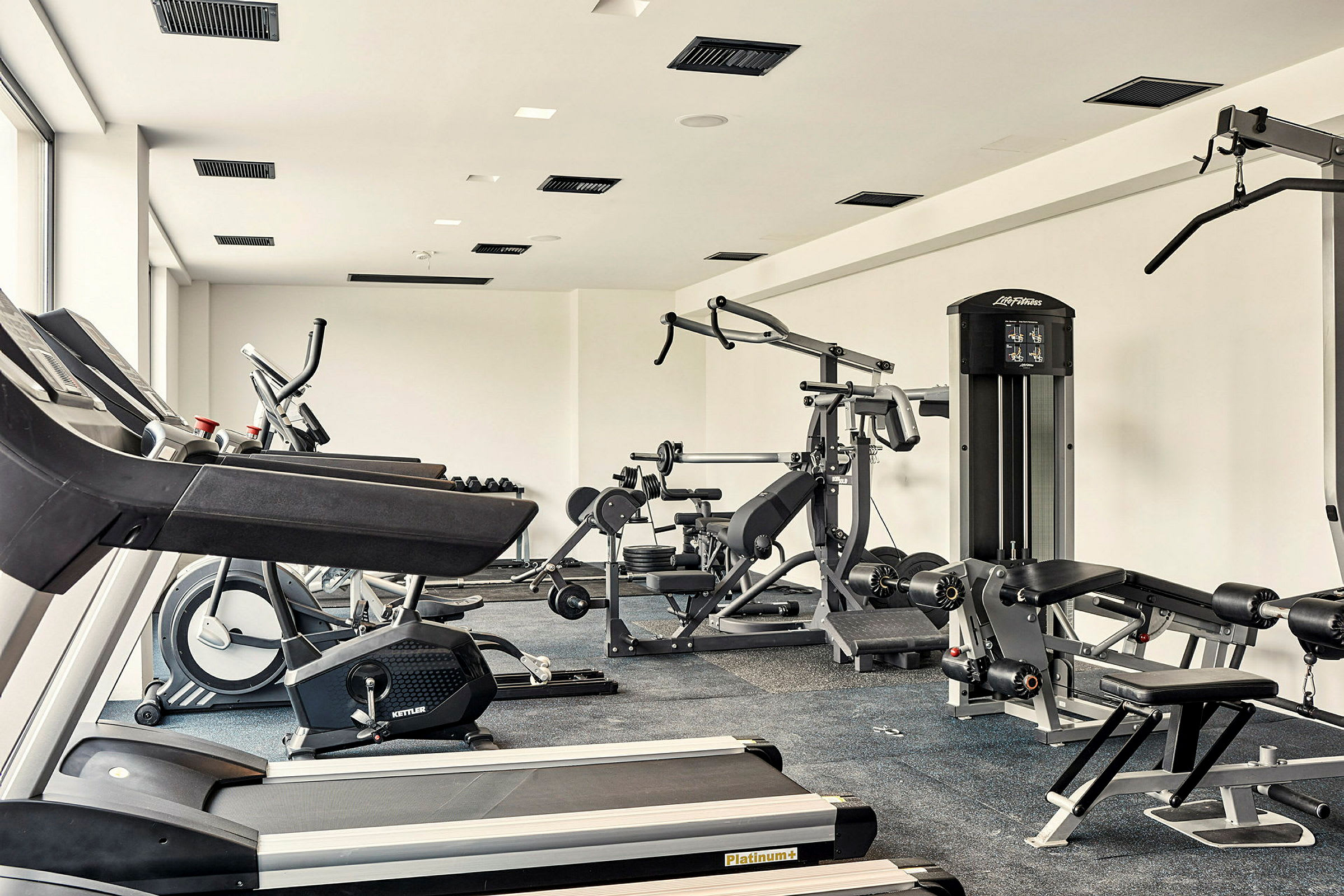 Et fitnesscenter med træningsmaskiner, løbebånd og vægte. (AI-genereret tekst)