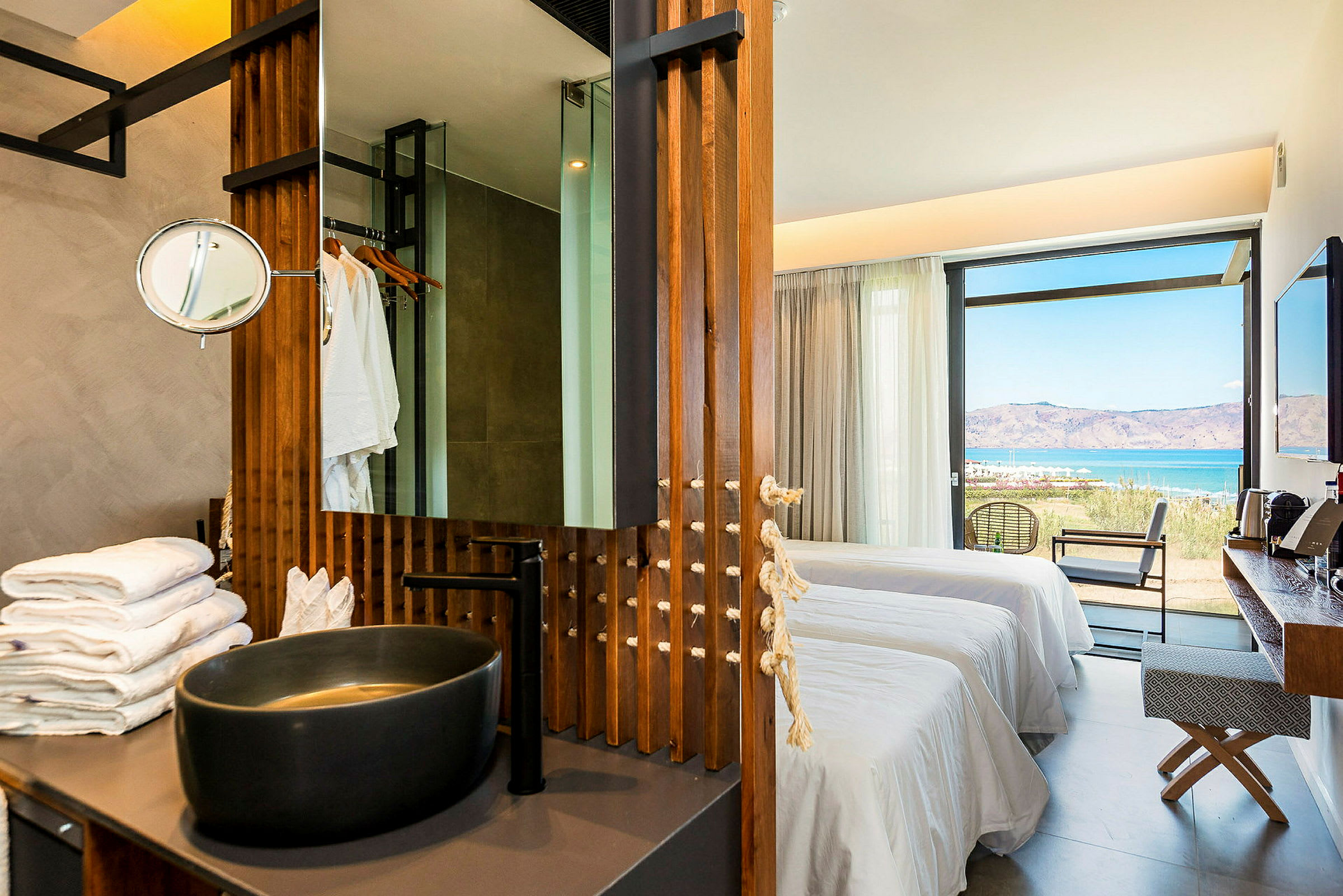 En moderne hotelsuite med skålformet håndvask, senge og udsigt til havet. (AI-genereret tekst)