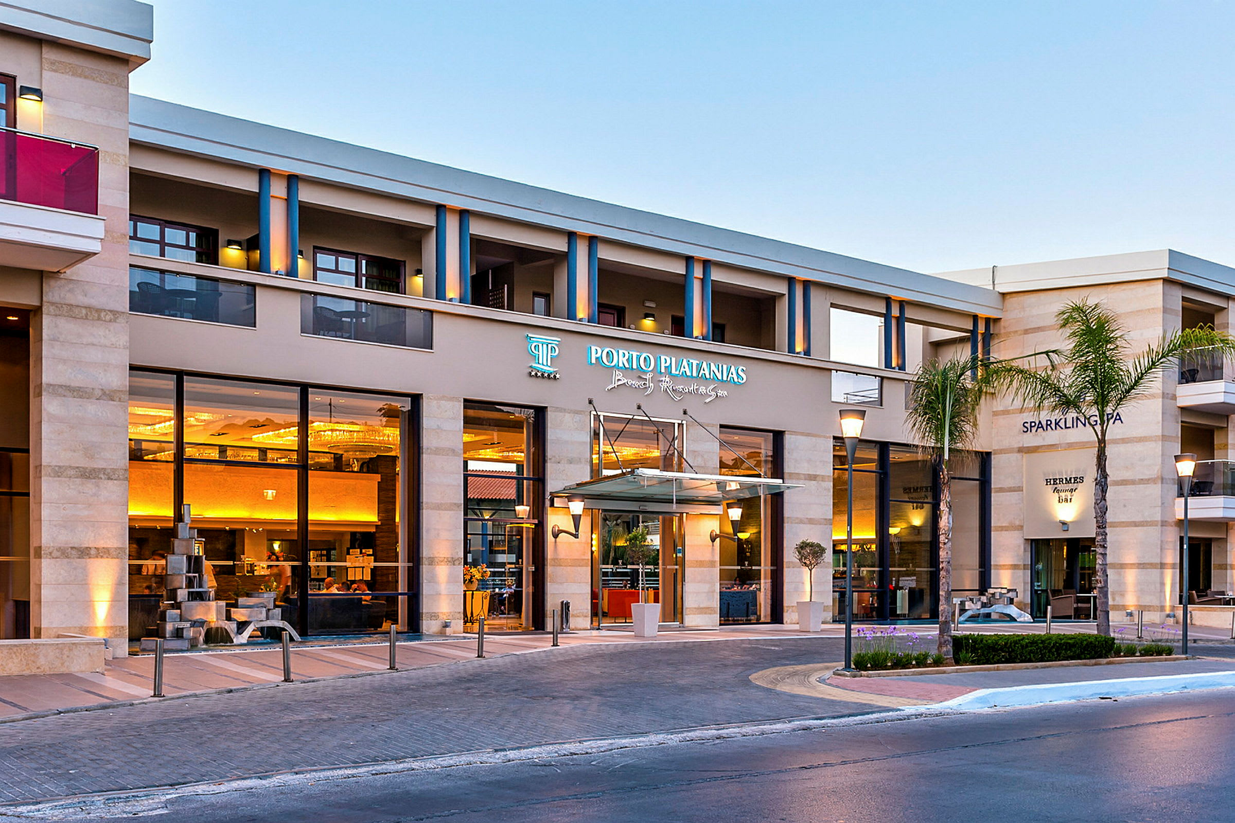 Hotelbygning med indgang skiltet som Porto Platanias Beach Resort & Spa. (AI-genereret tekst)