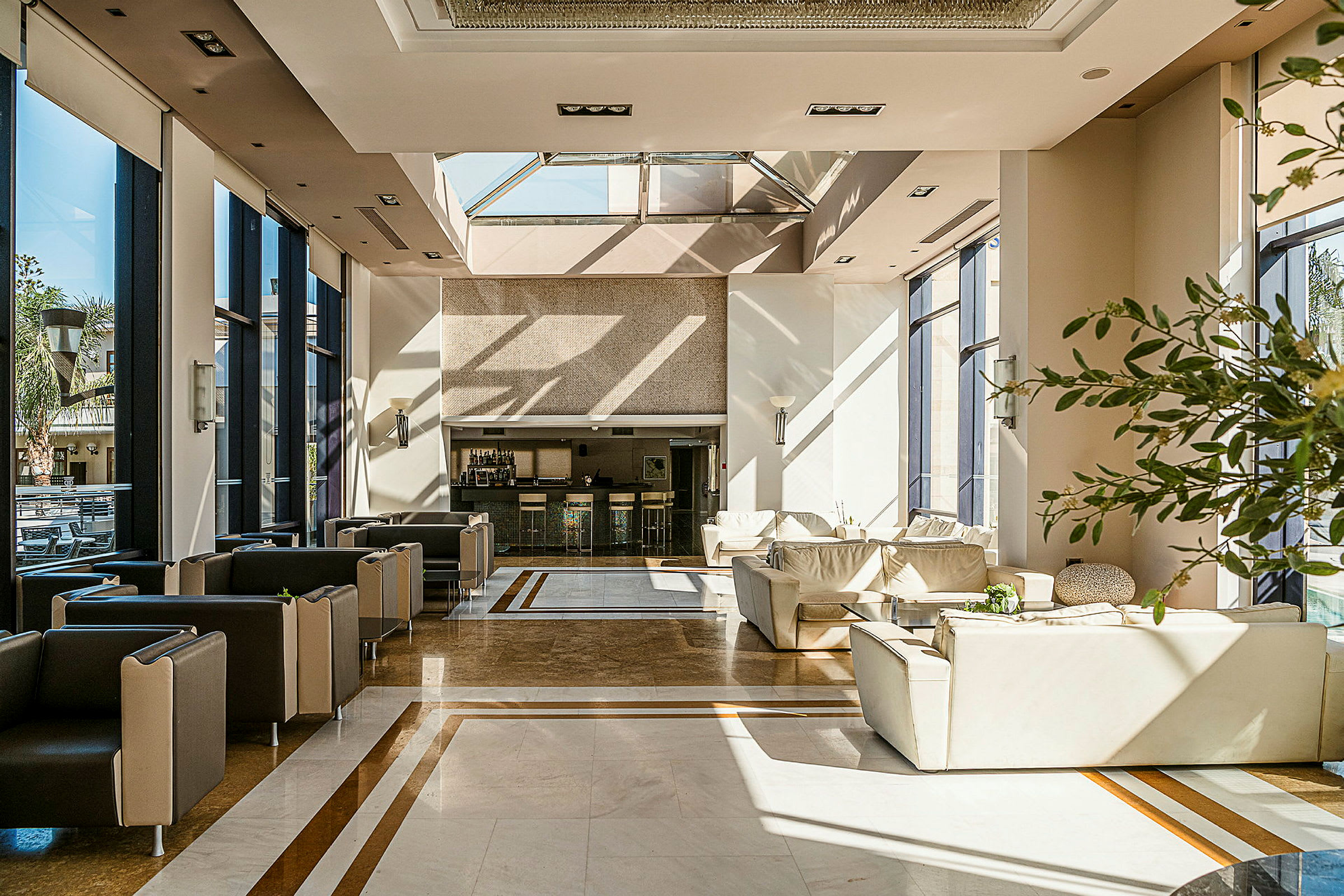 En lys og moderne indrettet hotellobby med store vinduer, komfortable siddemøbler og en reception. (AI-genereret tekst)