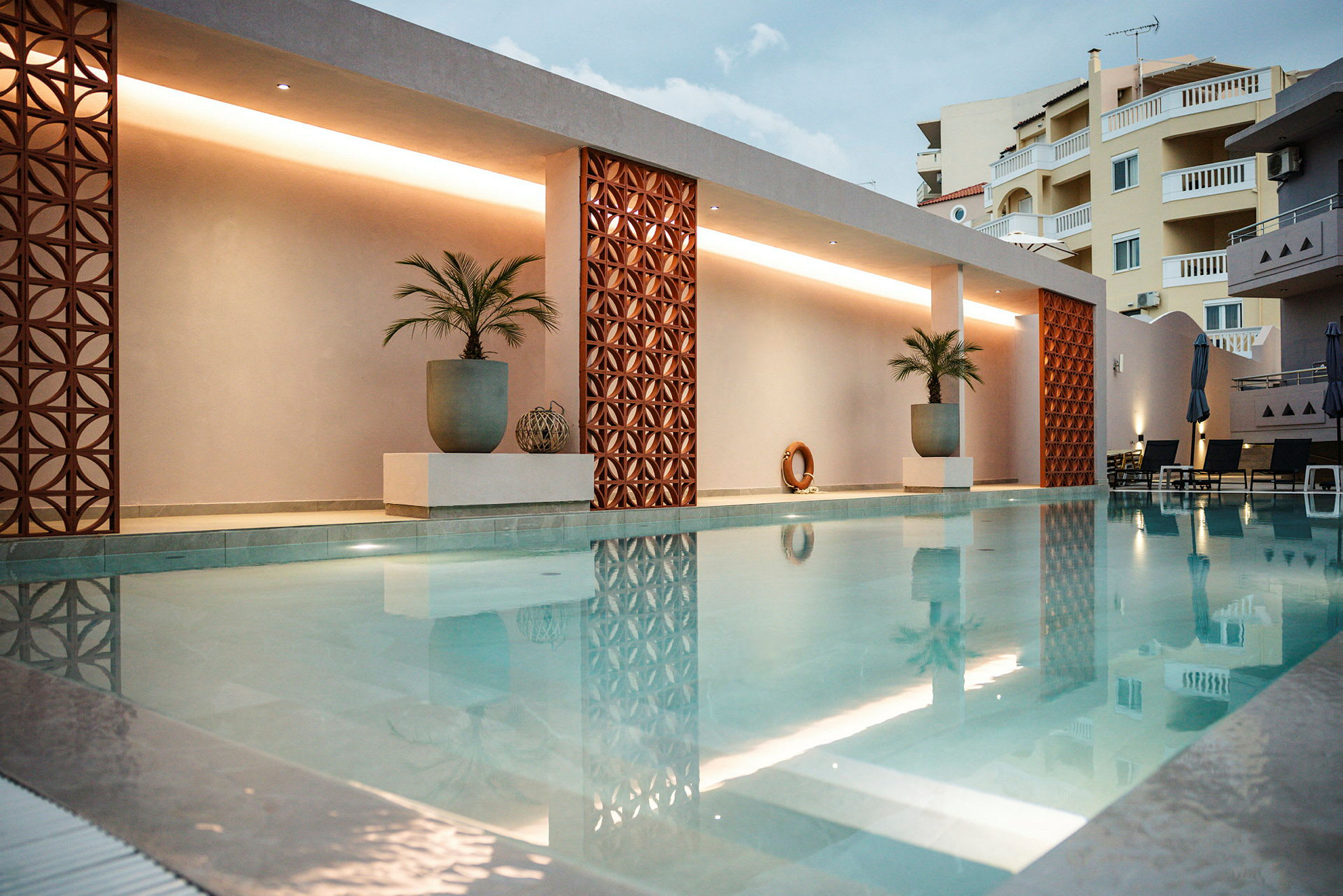 Moderne swimmingpool med dekorationer og palmer. (AI-genereret tekst)