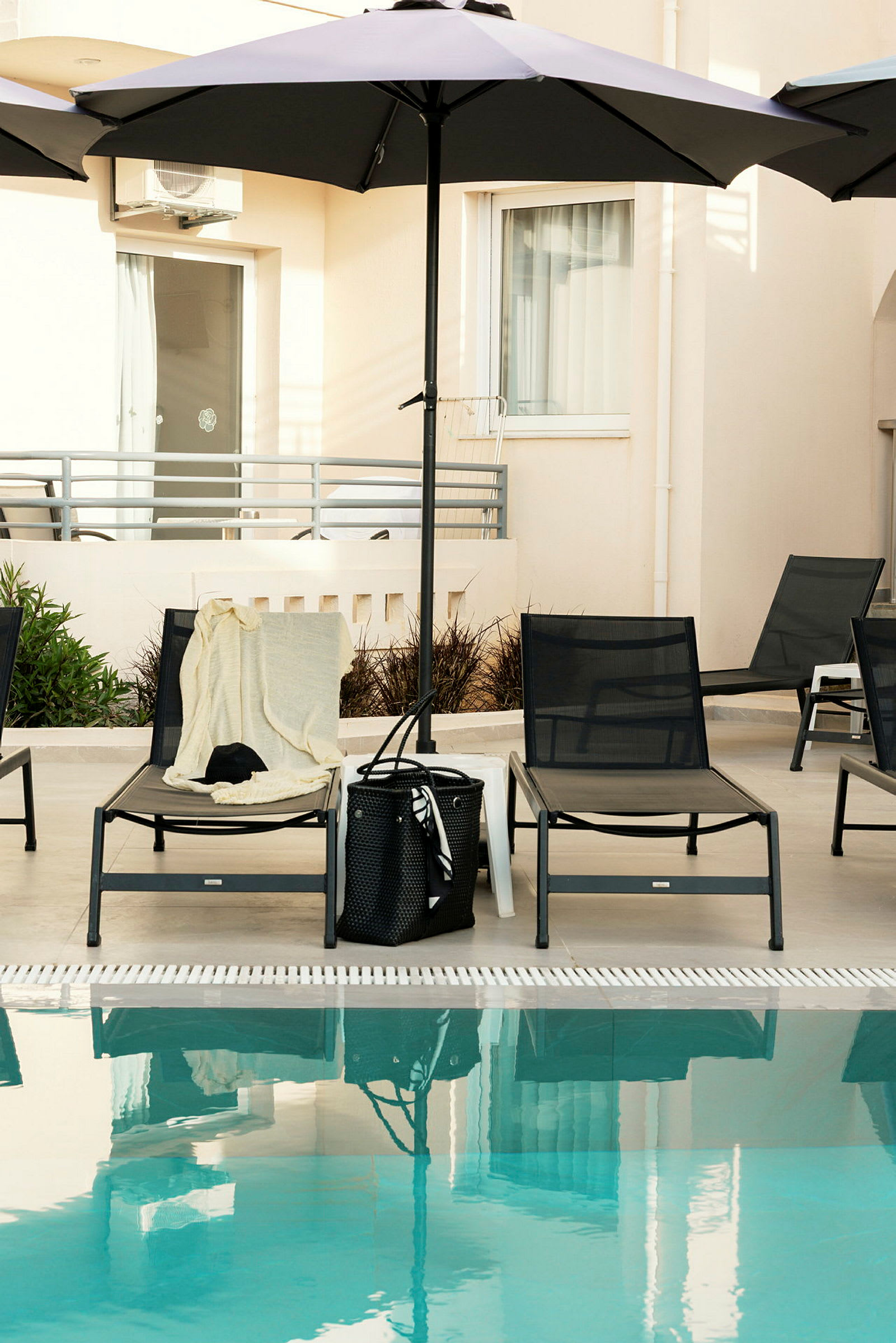 Liggestole med parasol ved en pool. (AI-genereret tekst)