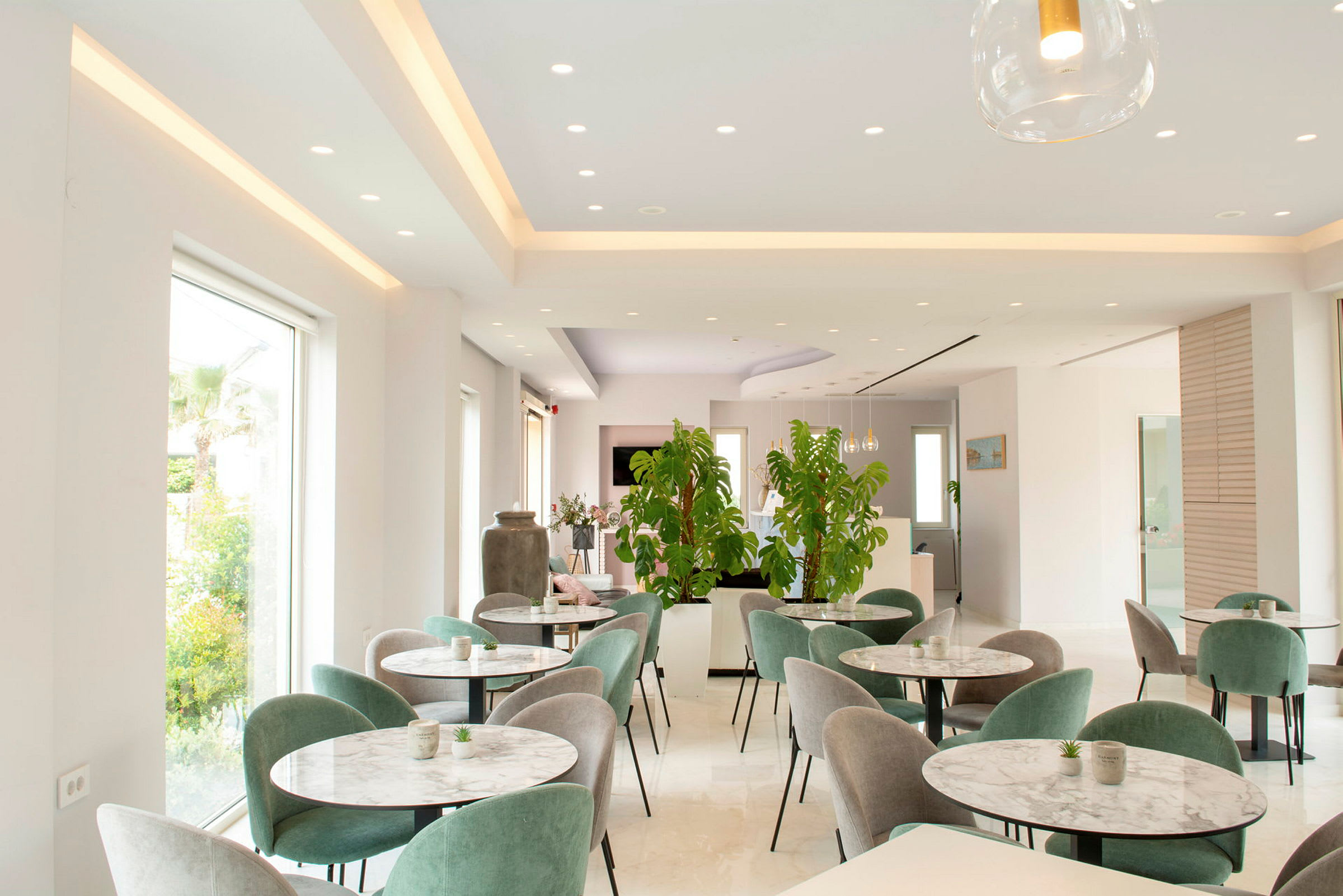 Moderne indrettet restaurant med grønne planter og flere borde. (AI-genereret tekst)