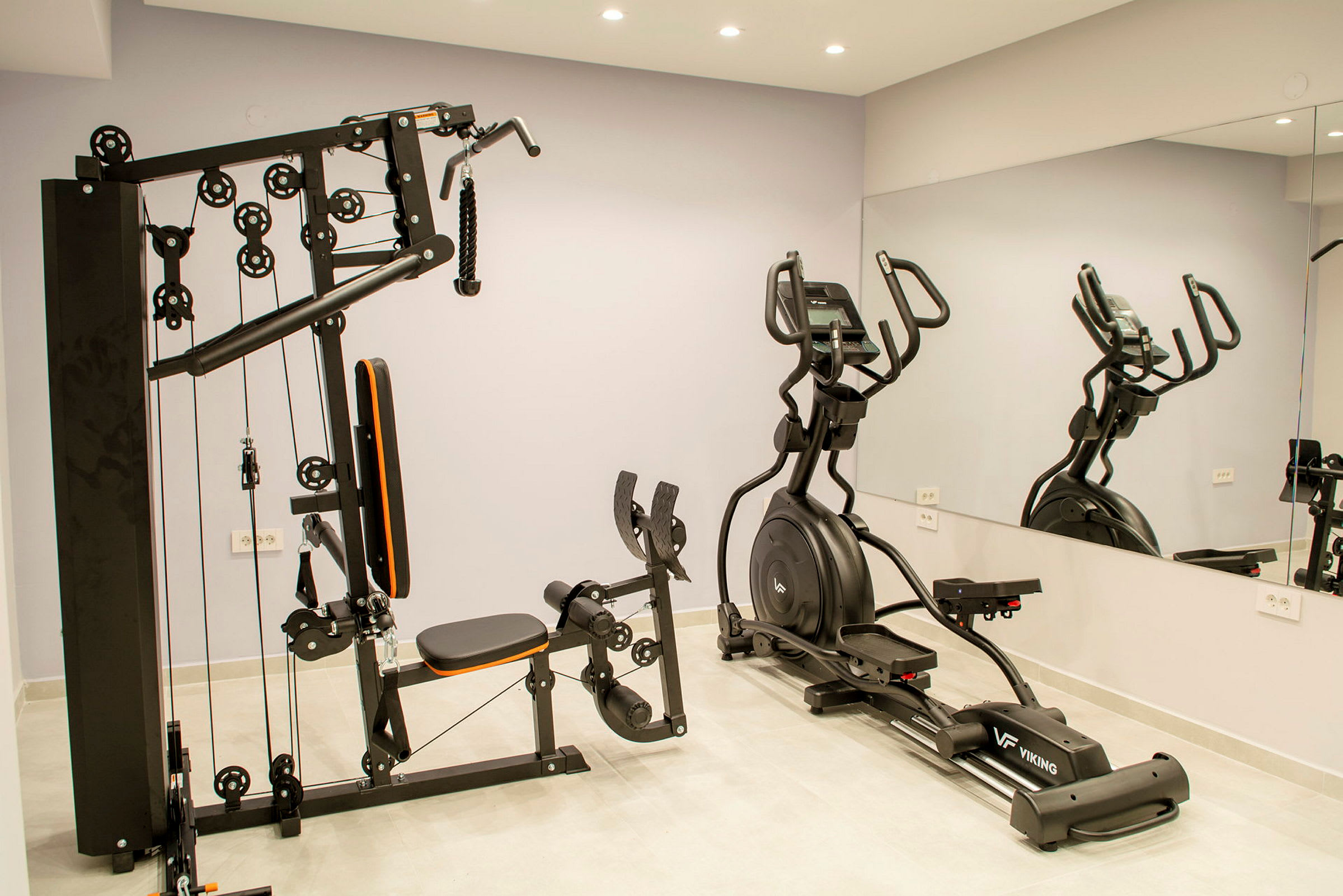 En træningsmaskine og en ellipsetræningsmaskine i et fitnesscenter. (AI-genereret tekst)