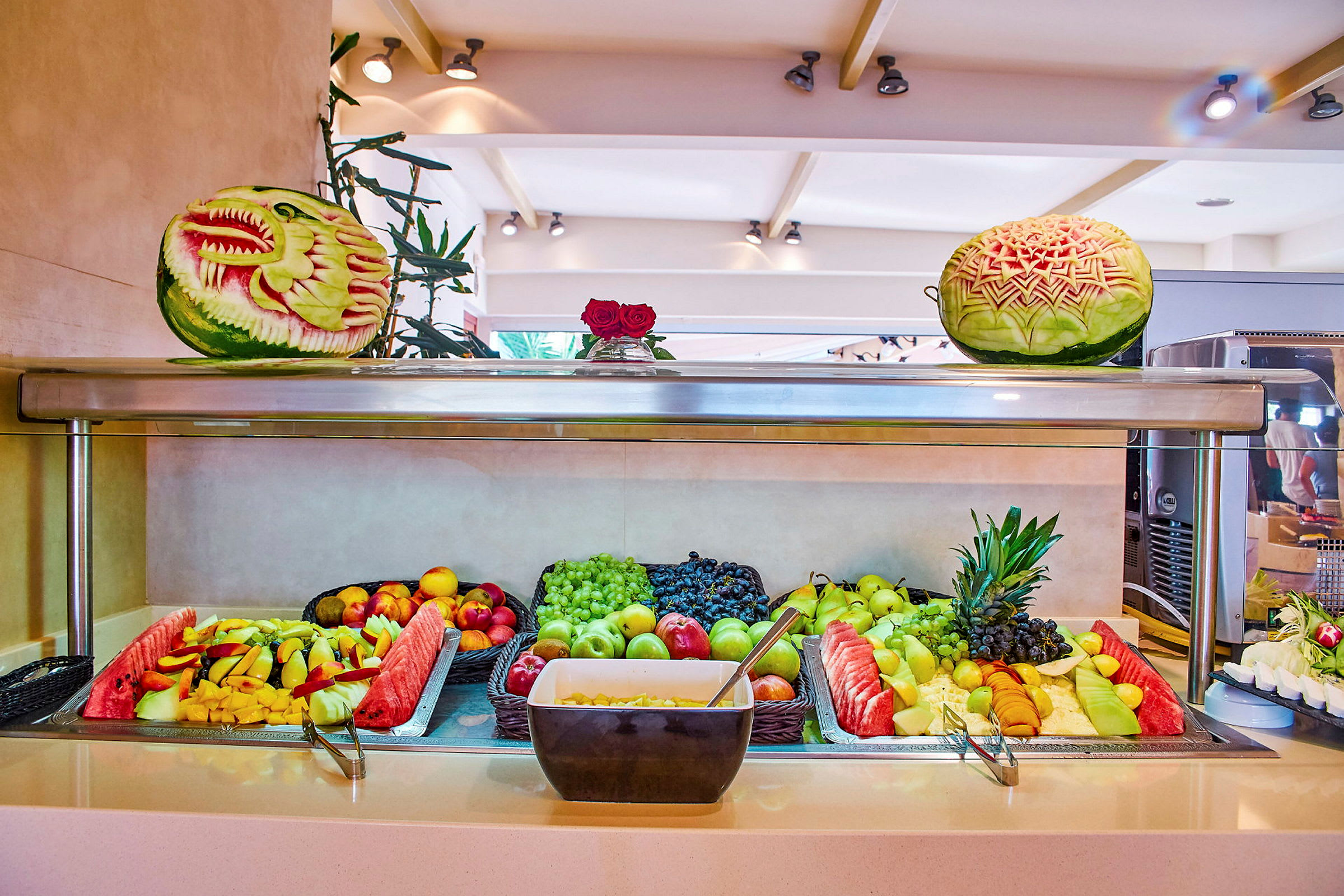 En buffet med frisk frugt, inklusive vandmelon og druer, samt dekorerede meloner. (AI-genereret tekst)