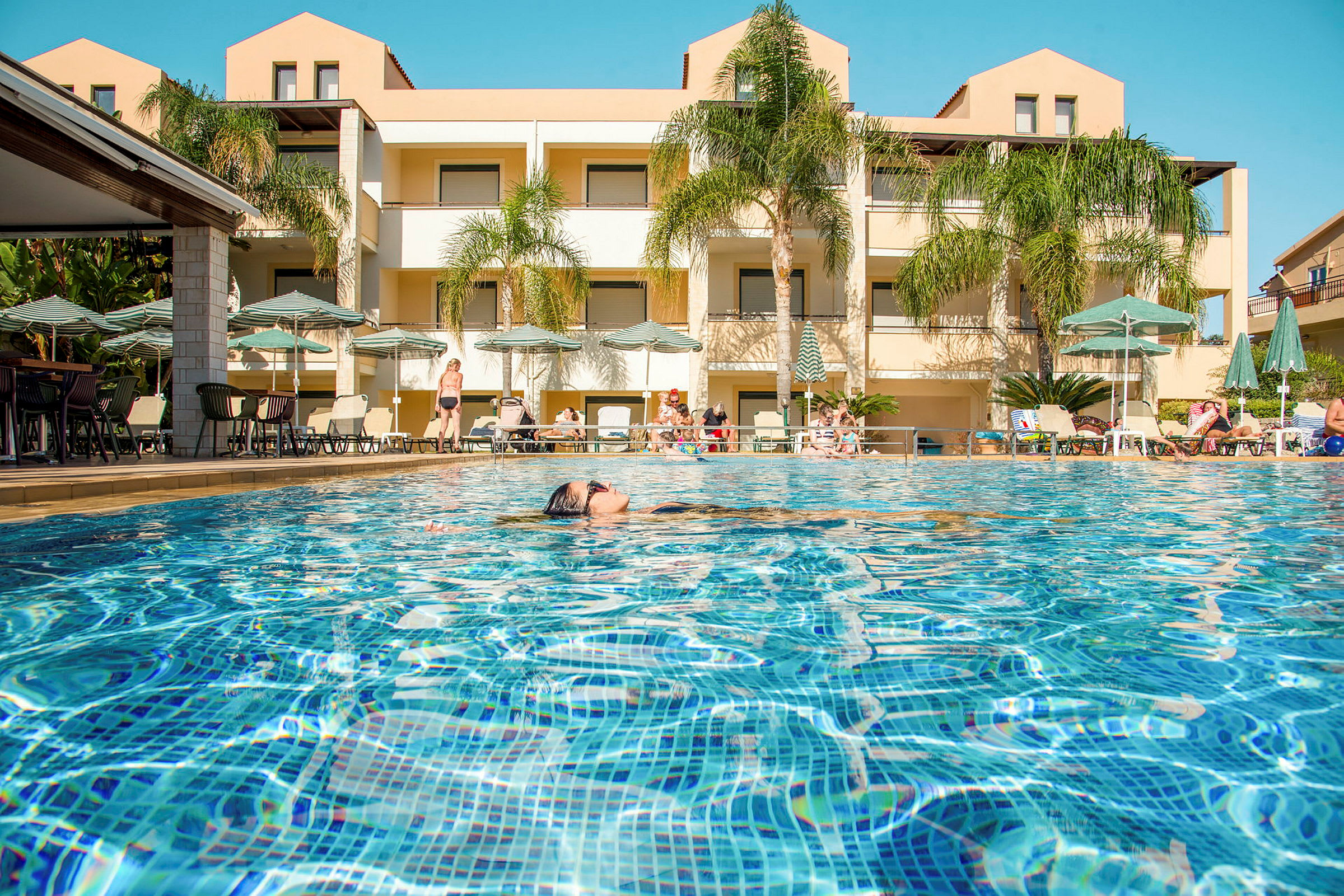 Billede af en pool med hotelbygningen i baggrunden. (AI-genereret tekst)