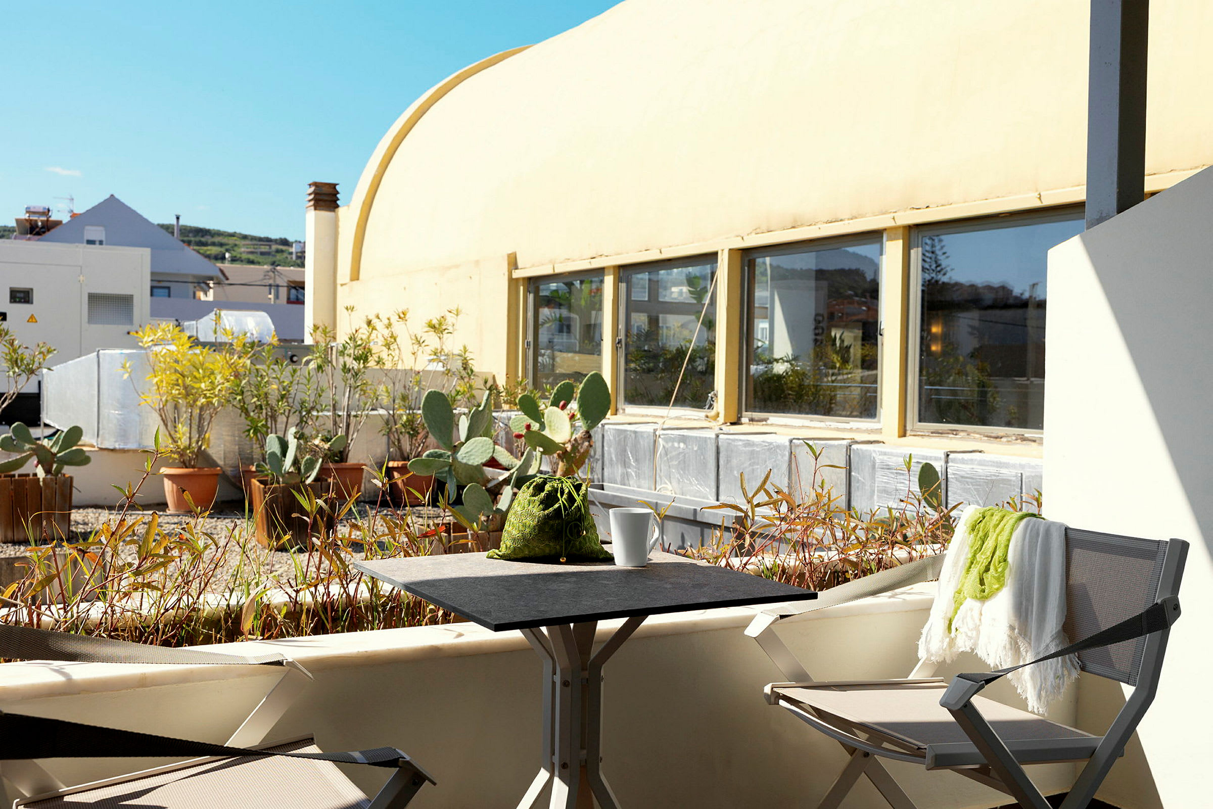 En solrig terrasse med stole, bord og planter i potter. (AI-genereret tekst)
