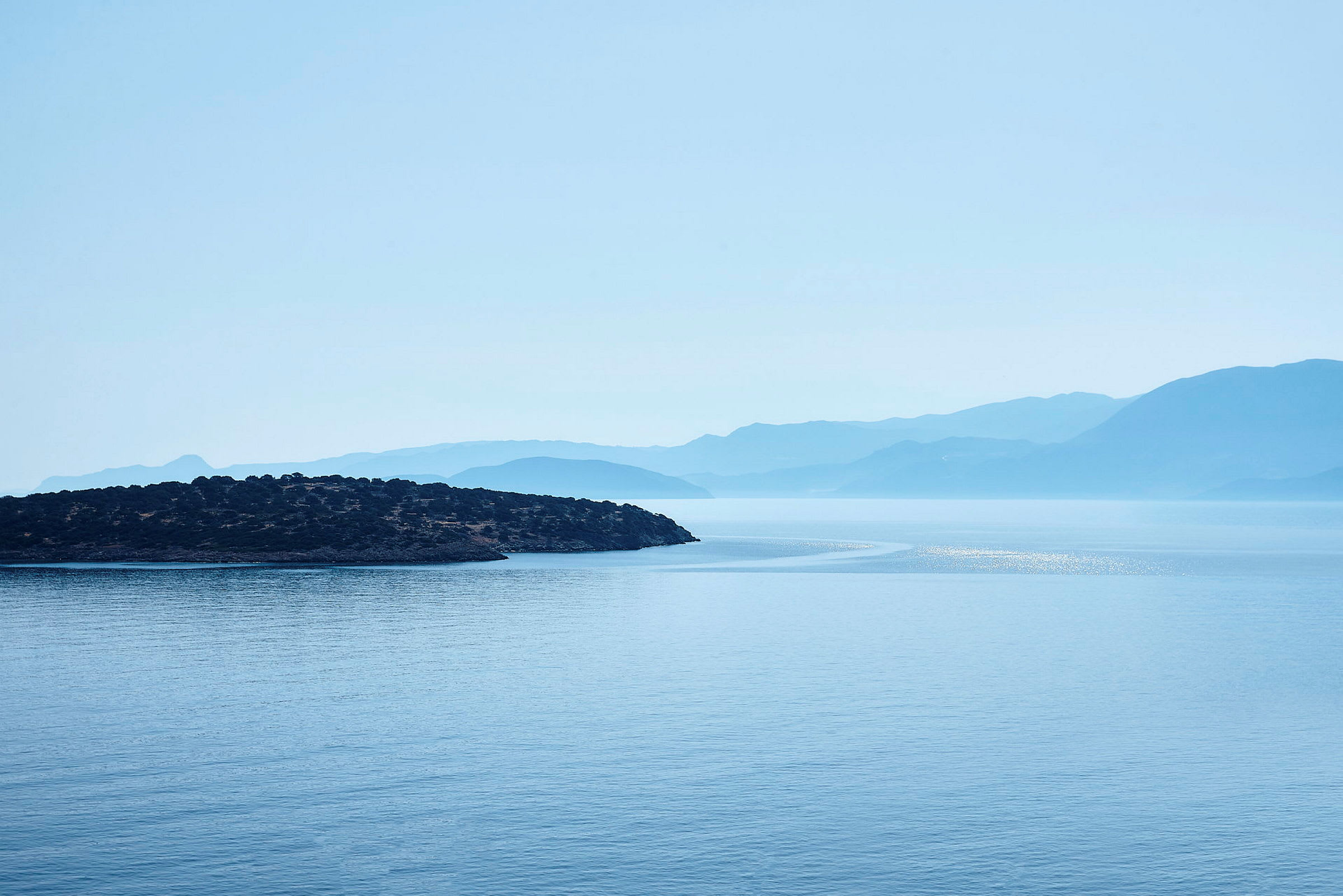 En udsigt over havet med en ø i forgrunden og bjerge i baggrunden. (AI-genereret tekst)