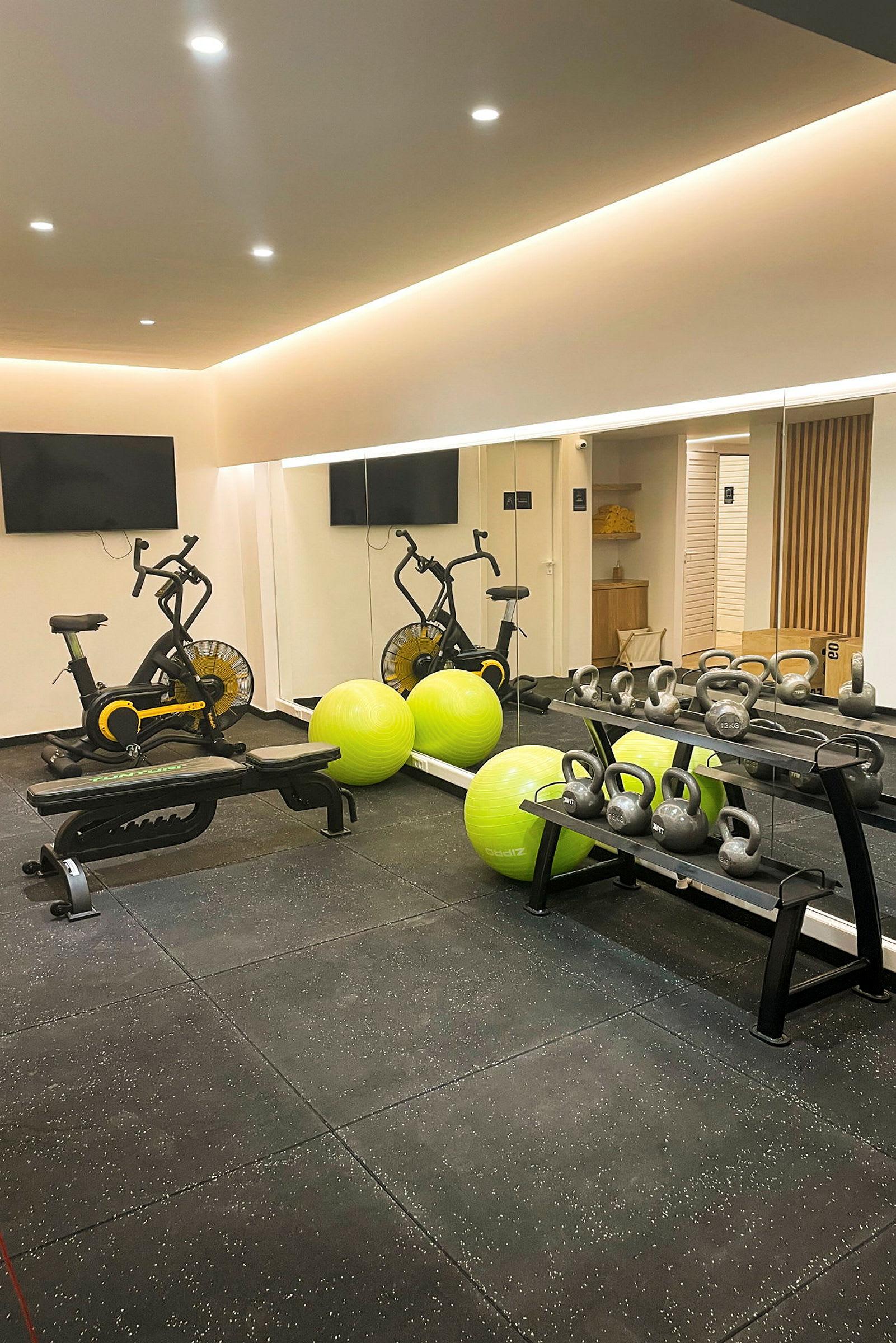 Et fitnesscenter med motionscykler, grønne træningsbolde og kettlebells. (AI-genereret tekst)