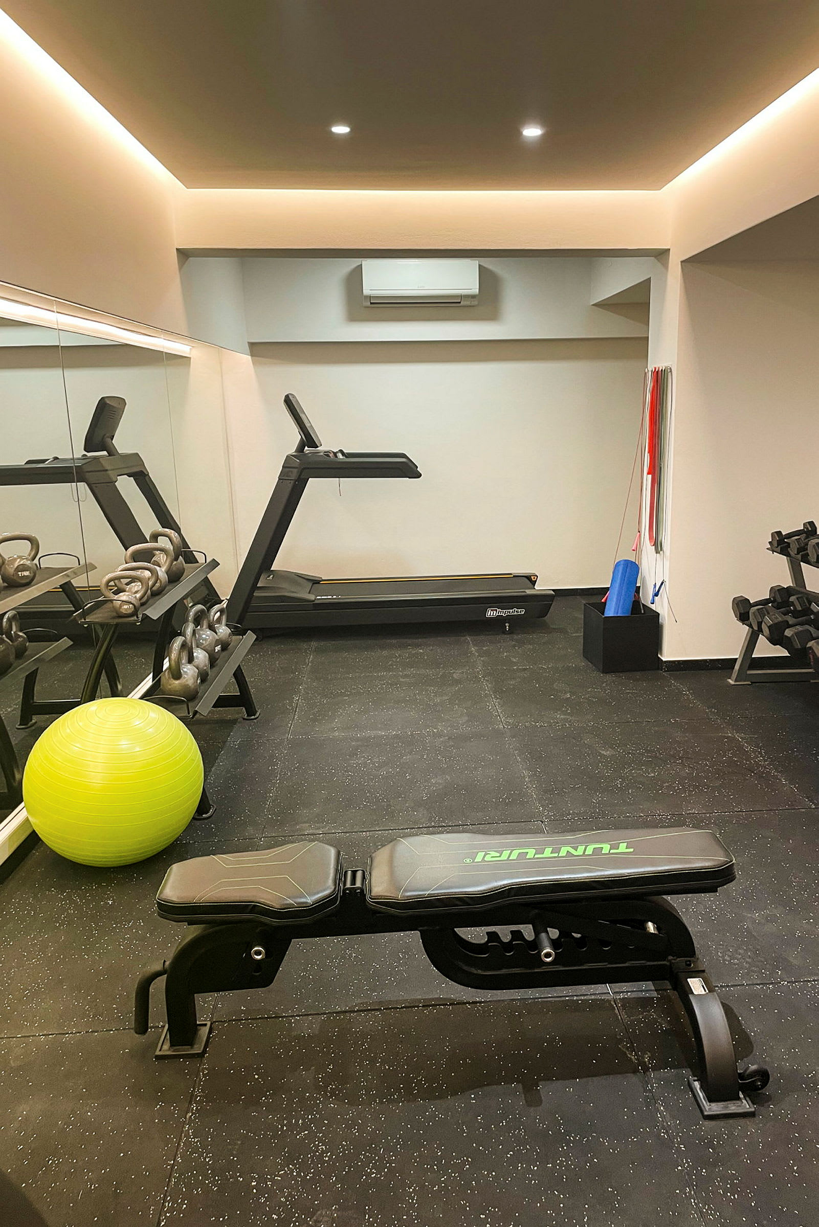 Et fitnesscenter med løbebånd, træningsbænk, kettlebells og pilatesbold. (AI-genereret tekst)