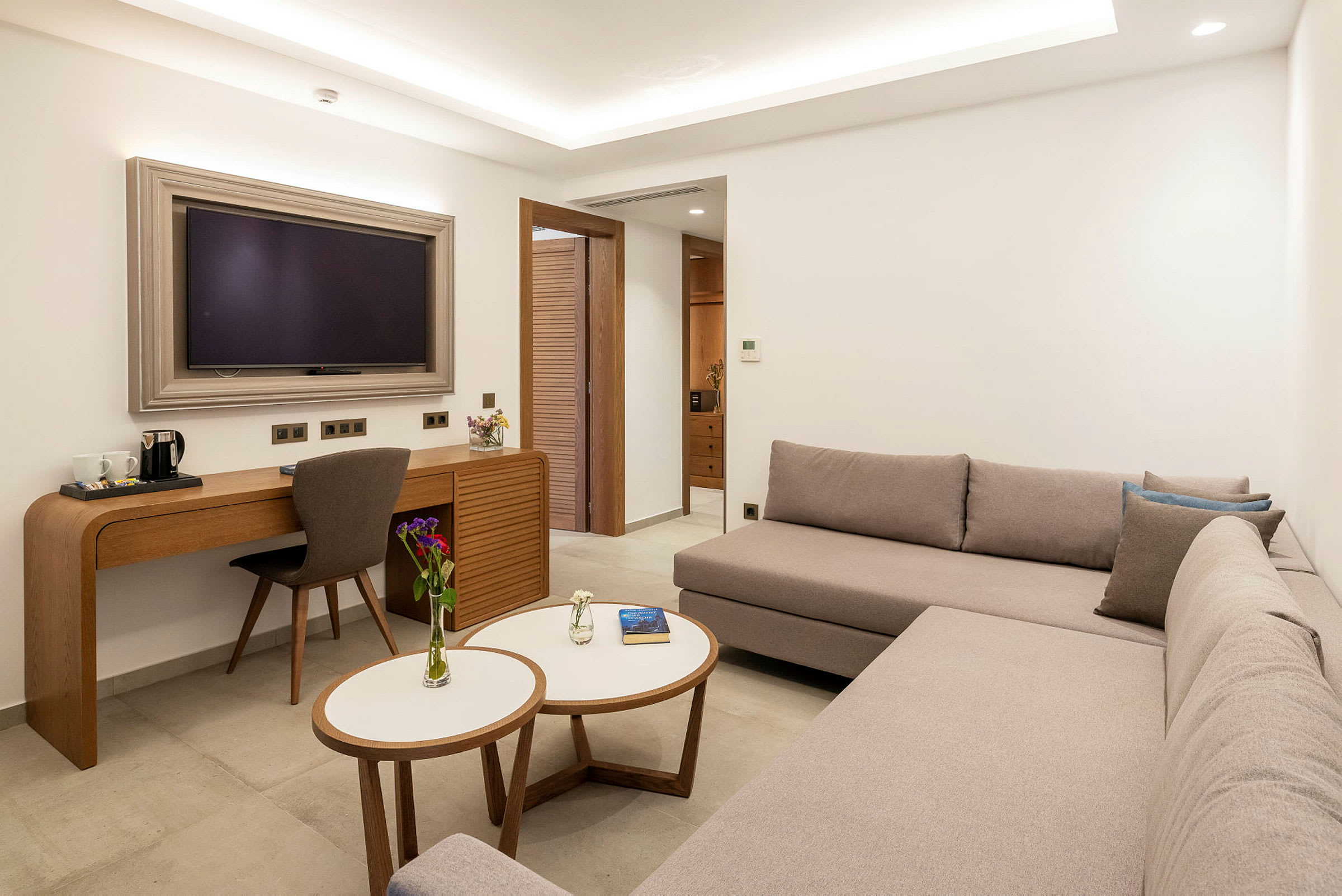 Et moderne hotelværelse med en sofa, et skrivebord og et TV. (AI-genereret tekst)