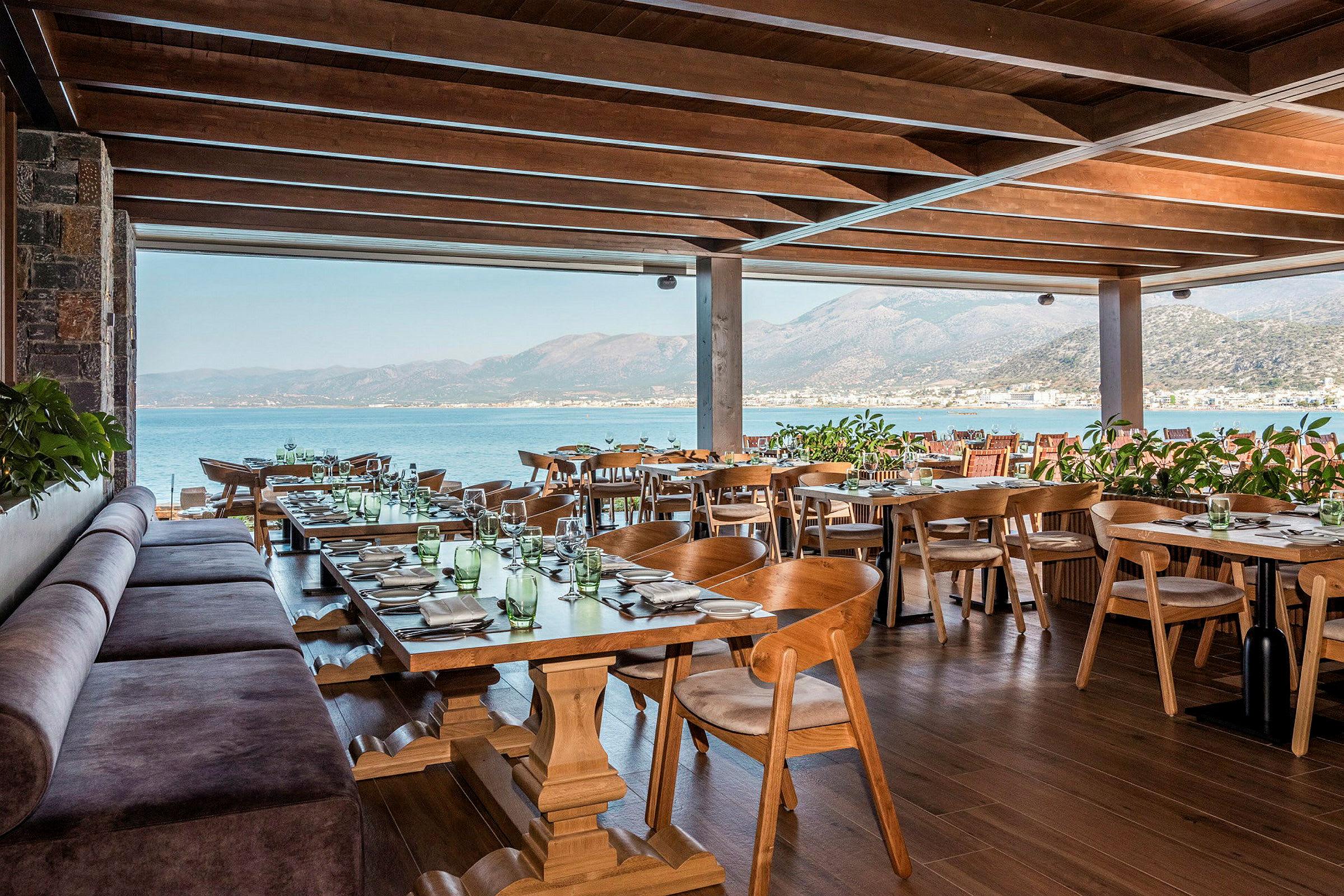 En restaurant med træborde og stole samt havudsigt. (AI-genereret tekst)