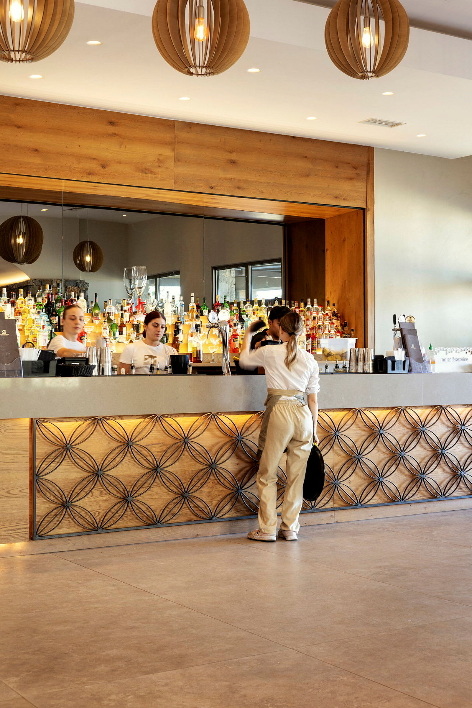 En bartender og kunder ved en elegant bar med flasker og glas i baggrunden. (AI-genereret tekst)