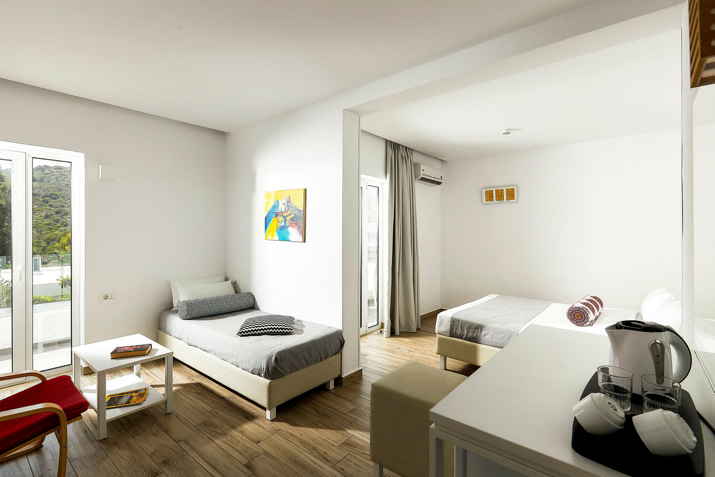 Billede af et hotelværelse med to enkeltsenge, lyse vægge og møbler samt et bord med elektroniske faciliteter. (AI-genereret tekst)