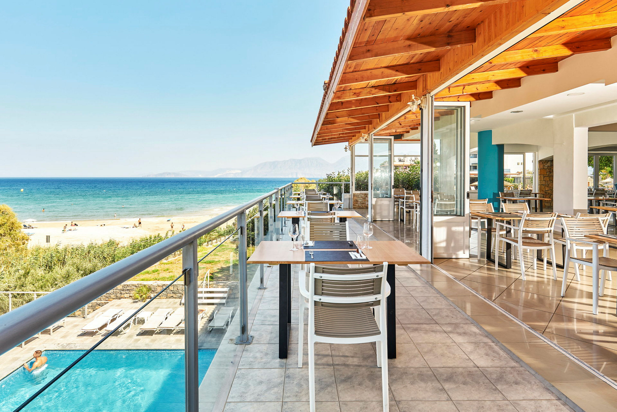 Udendørs servering på en restaurant med udsigt over havet og stranden. (AI-genereret tekst)