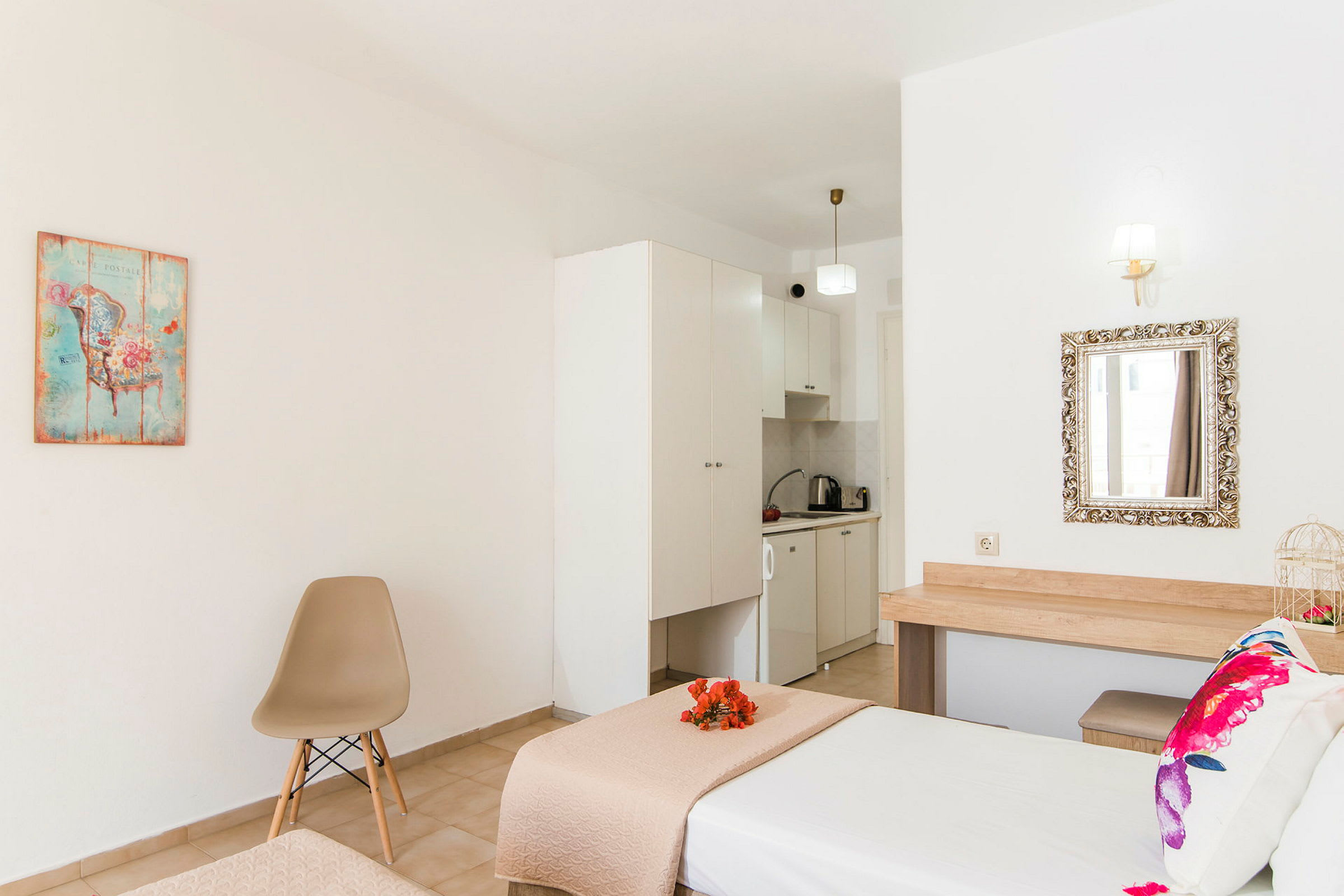 Et hotelværelse med seng, stol, dekorativ billedtavle og et lille køkkenområde. (AI-genereret tekst)