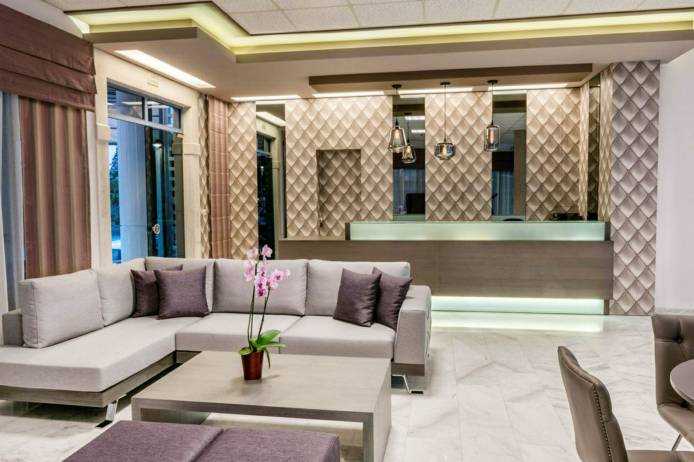 Hotellobbyen med moderne indretning, inklusive en sofa og et receptionsområde med designvæg og lamper. (AI-genereret tekst)