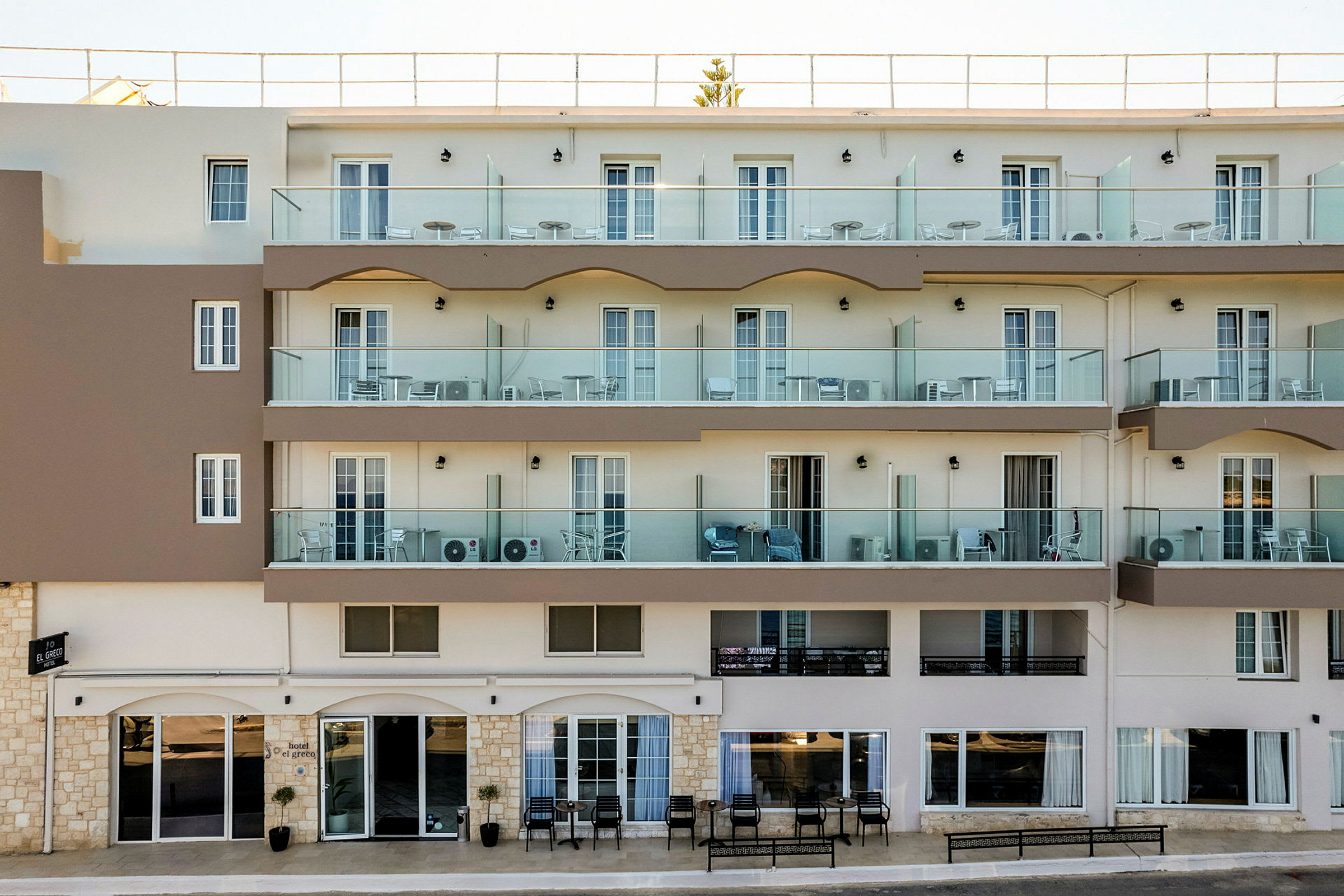 Hotellets facade med altaner og indgang på stueetagen. (AI-genereret tekst)