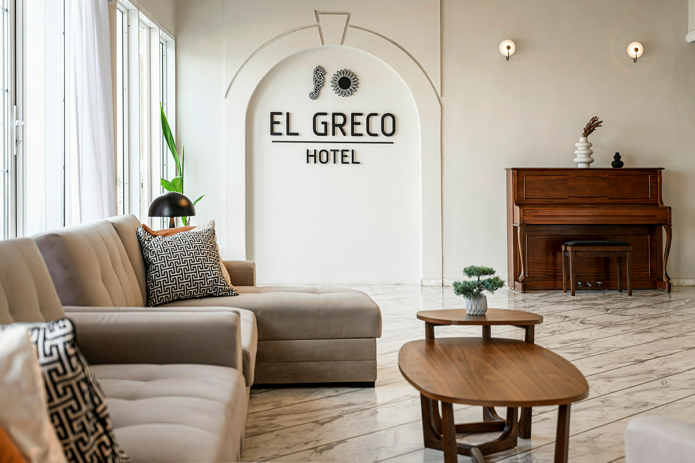 Interiør af et hotel med sofaer, borde og et klaver. (AI-genereret tekst)